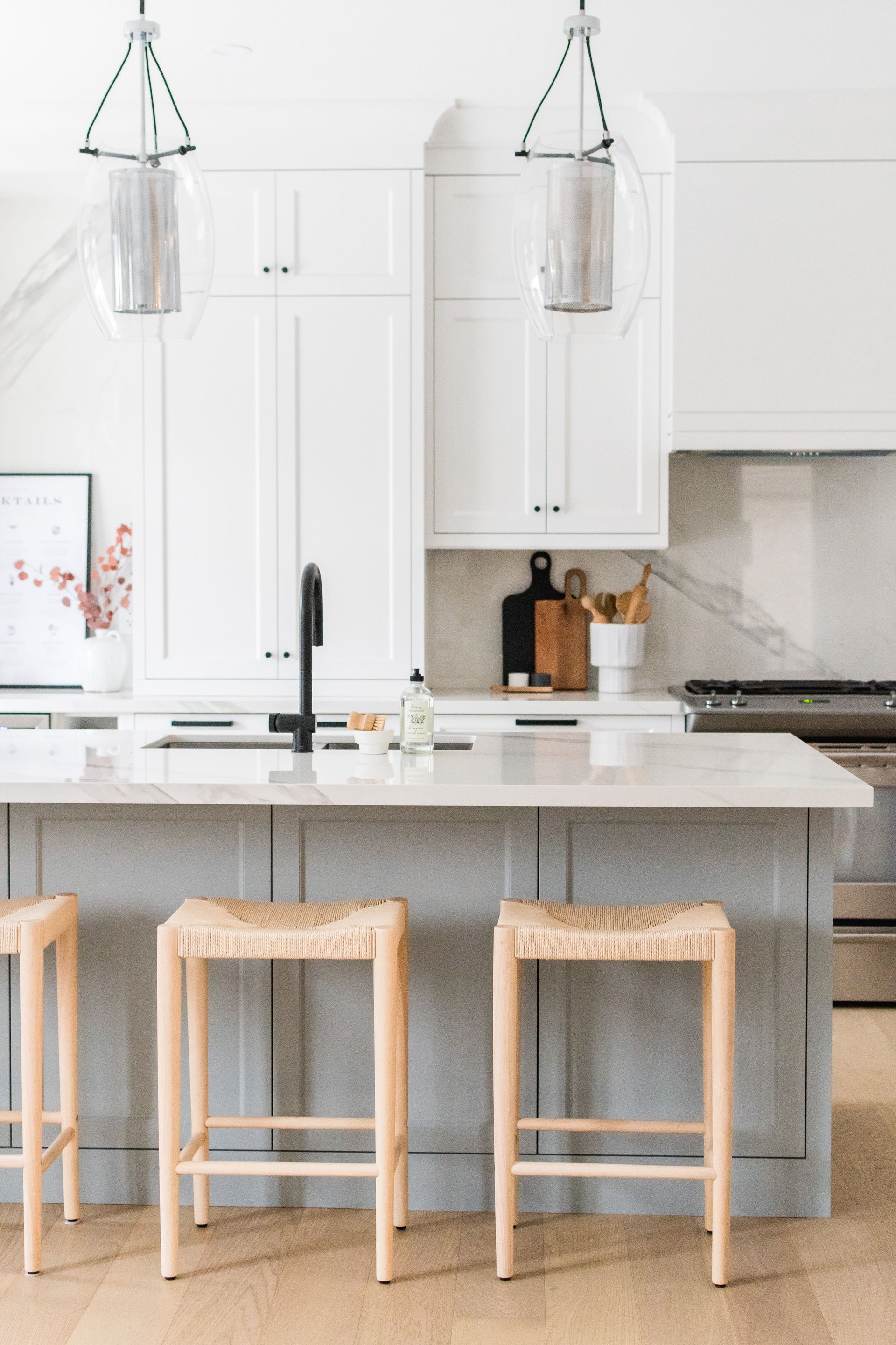 A kitchen with a large island and three stools.