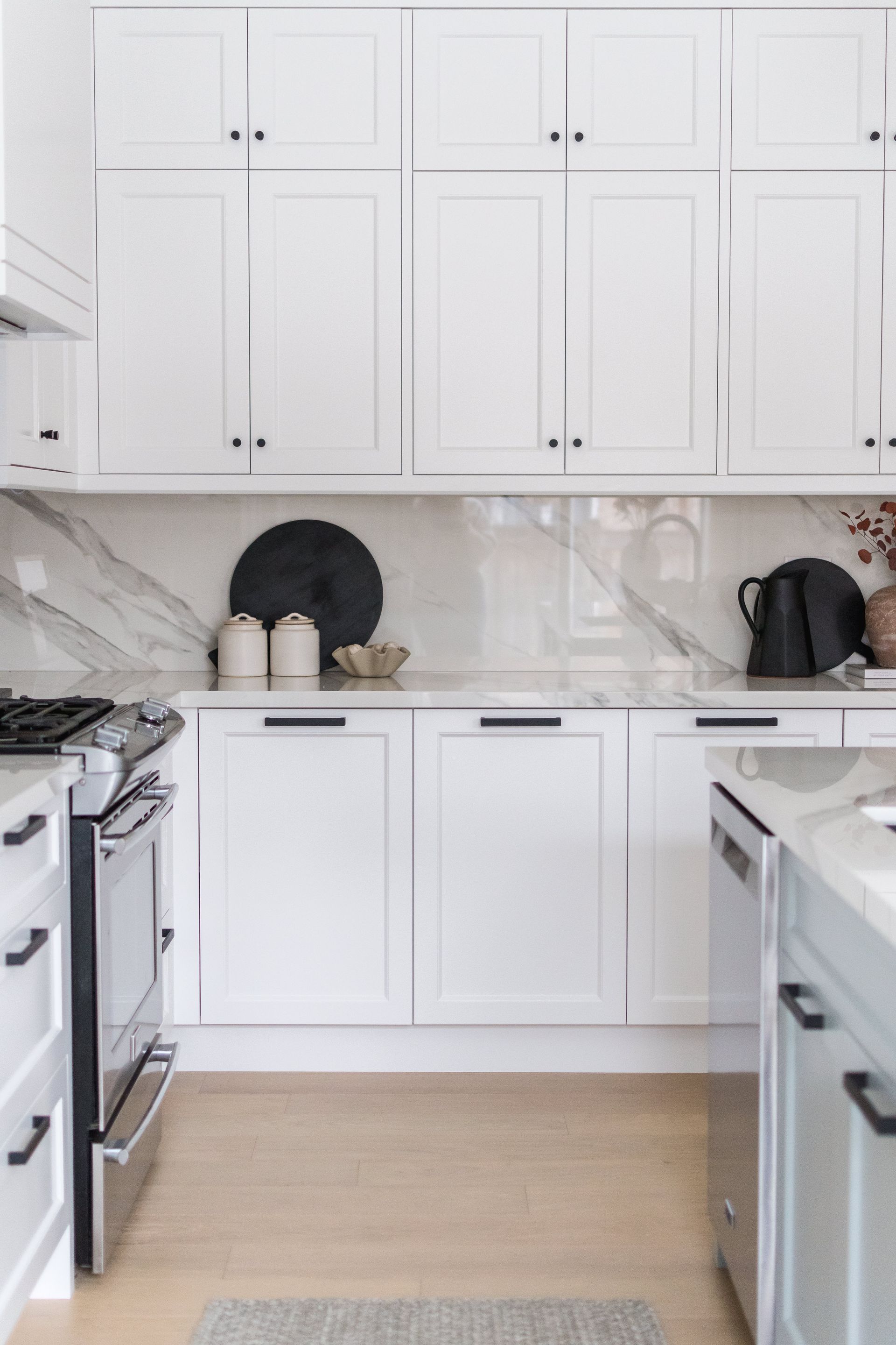 A kitchen with white cabinets , a stove , and a dishwasher.