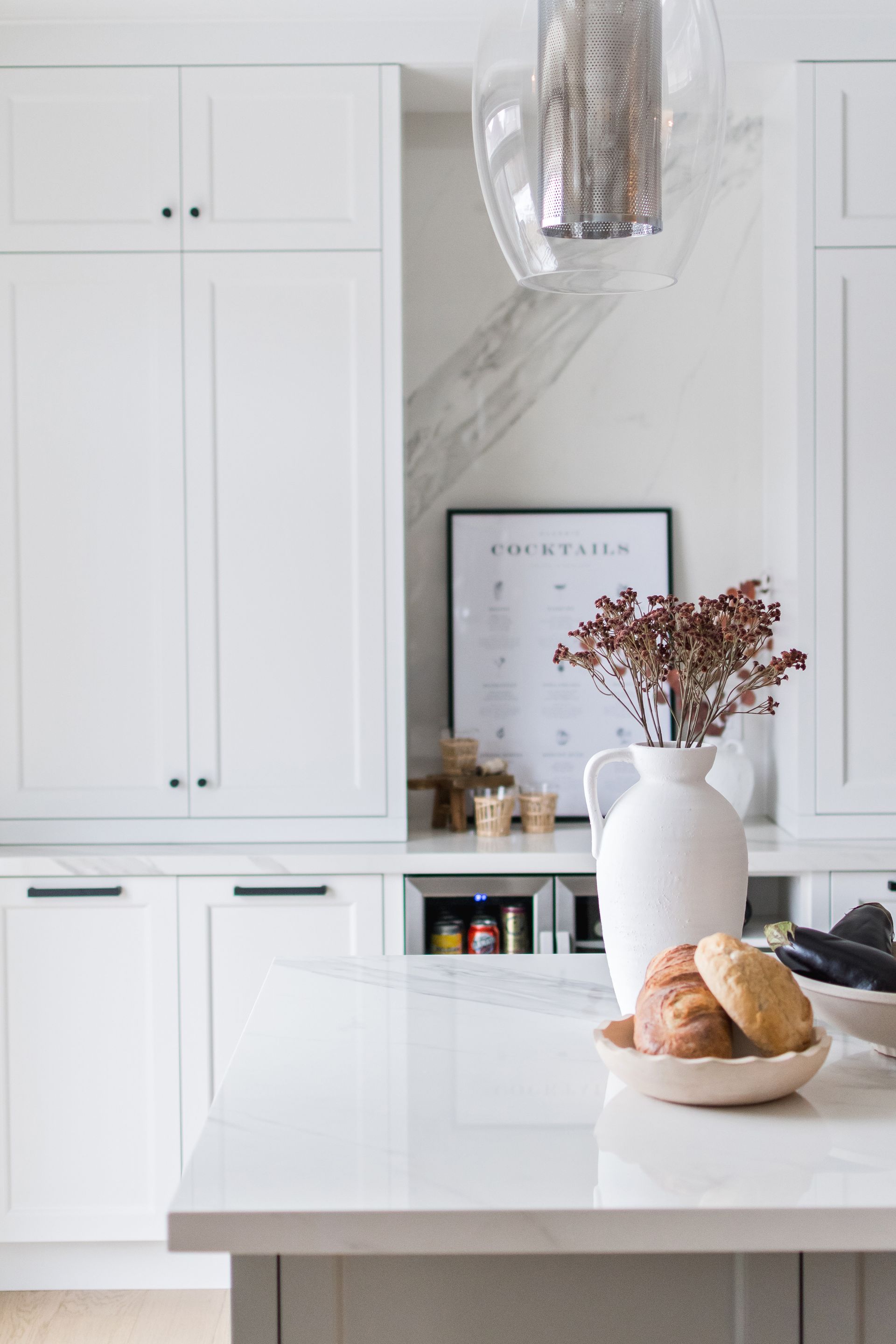 A kitchen counter with a vase of flowers and bread on it.