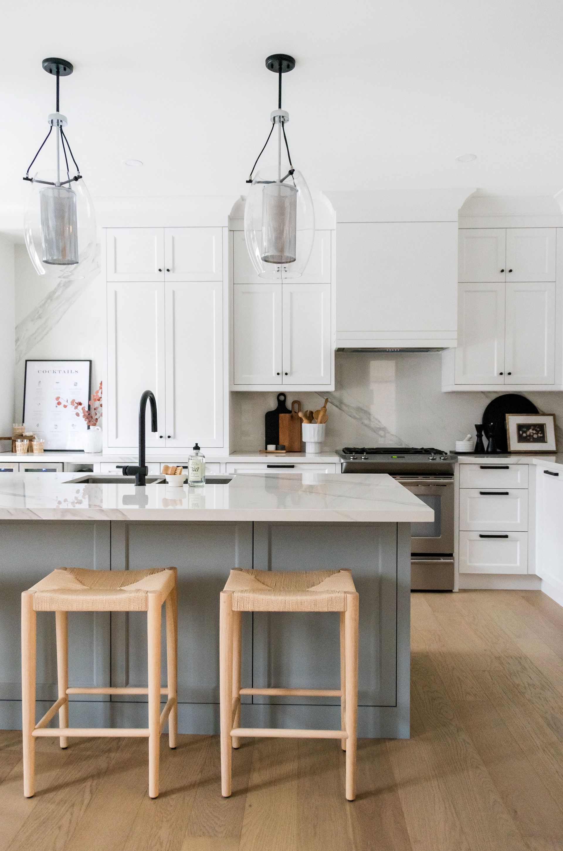 A kitchen with a large island and three wicker stools.