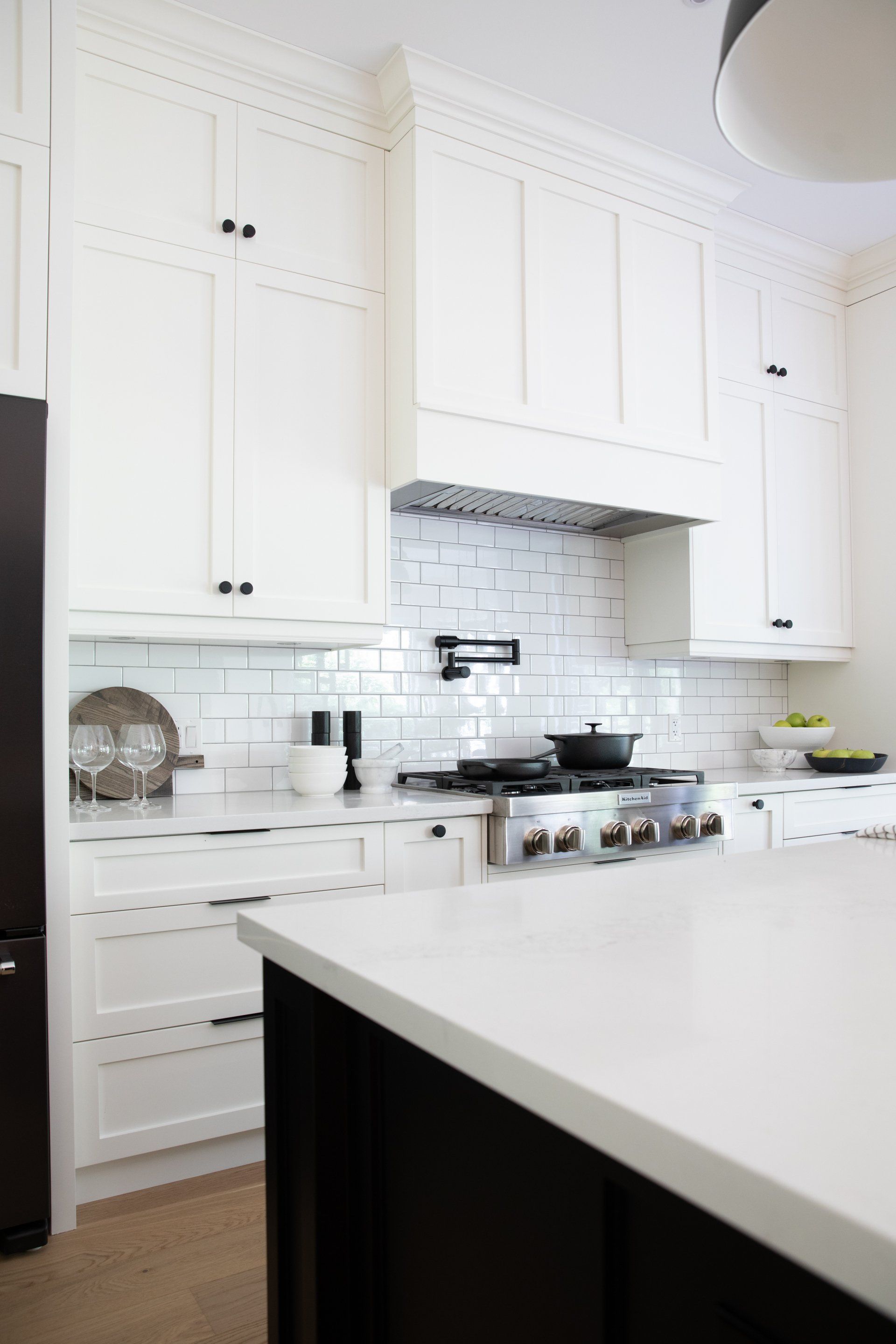 A kitchen with white cabinets , black appliances , a stove and a refrigerator.