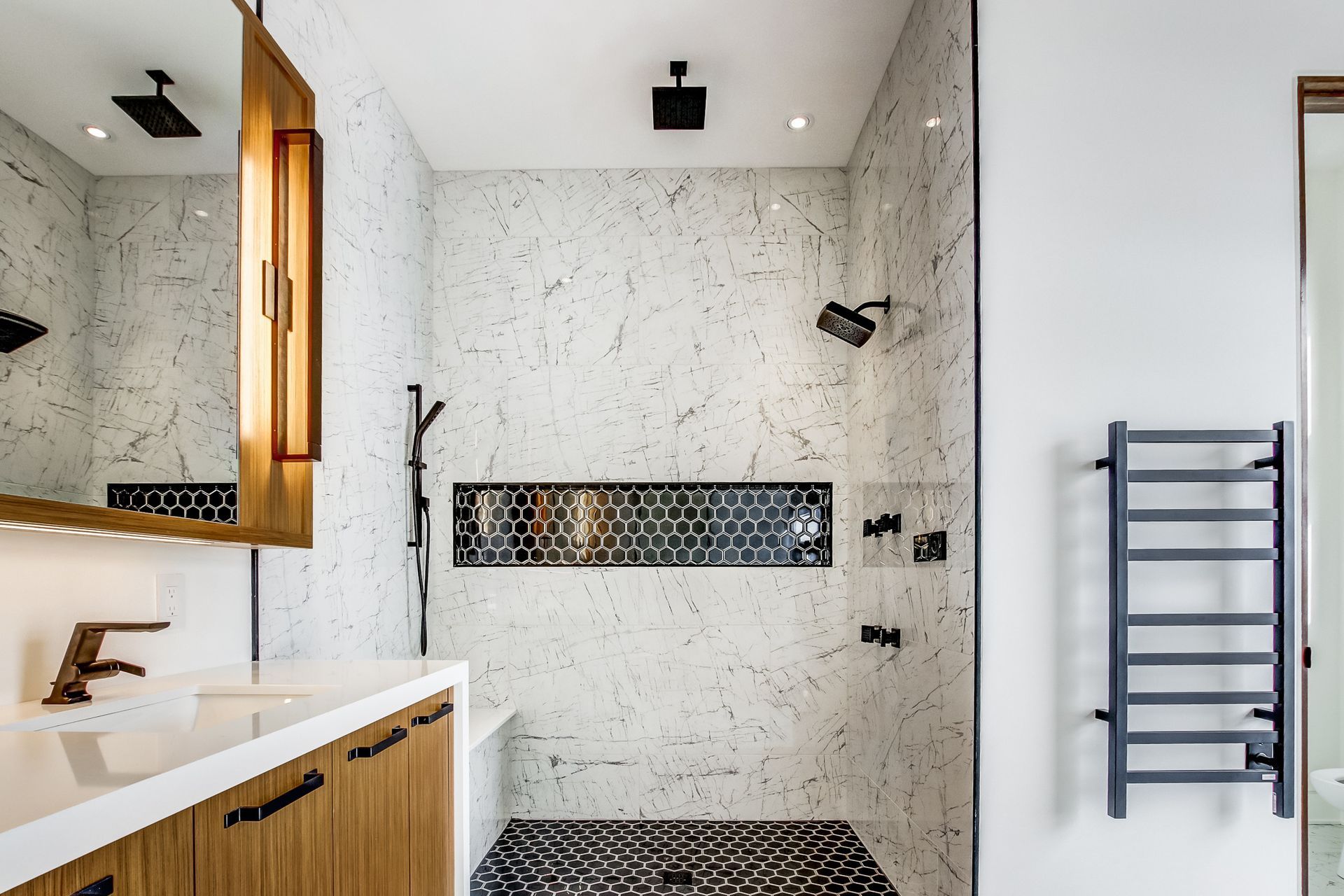 A bathroom with a walk in shower , sink , mirror and towel rack.