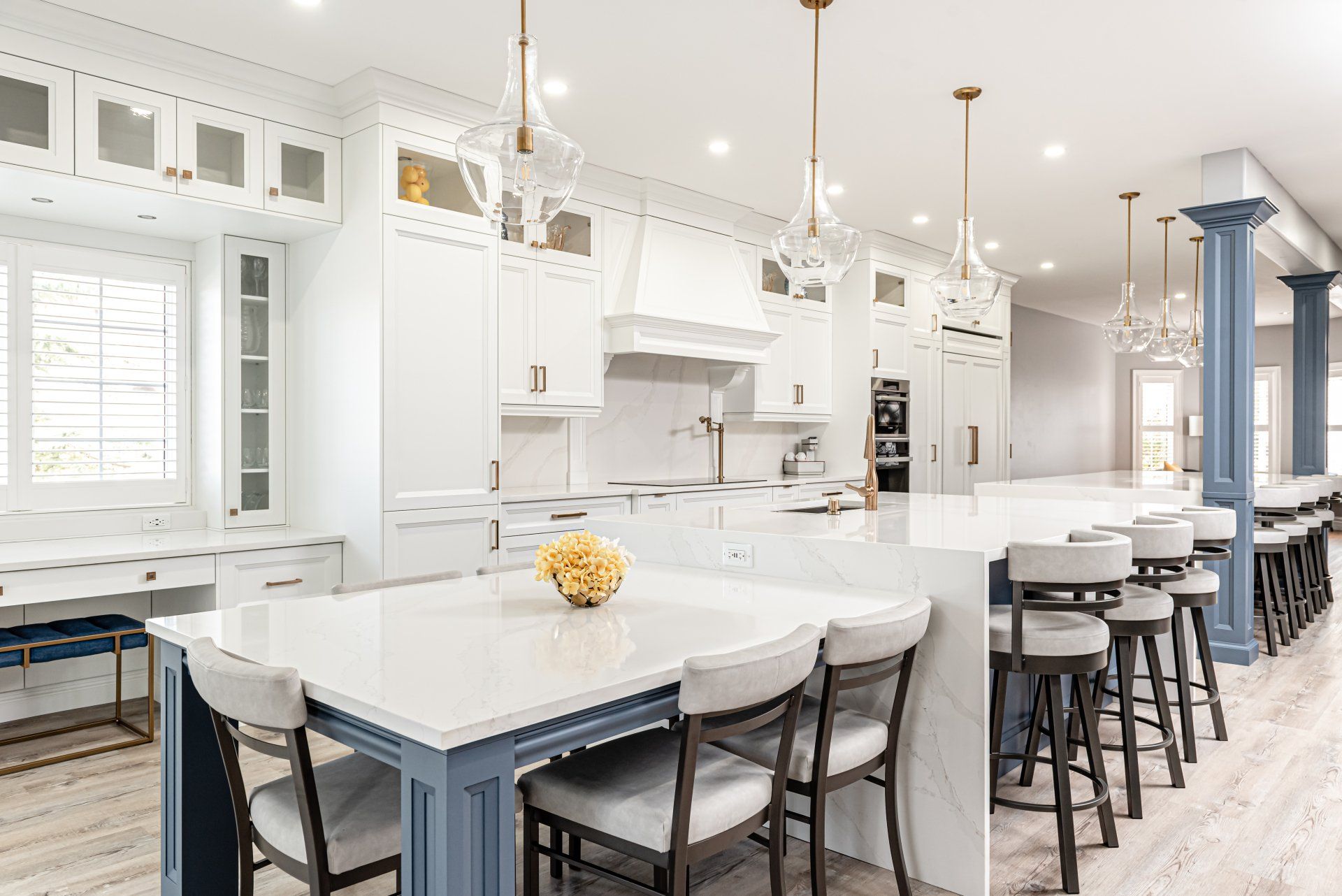 A kitchen with white cabinets , a blue island , a table and chairs.
