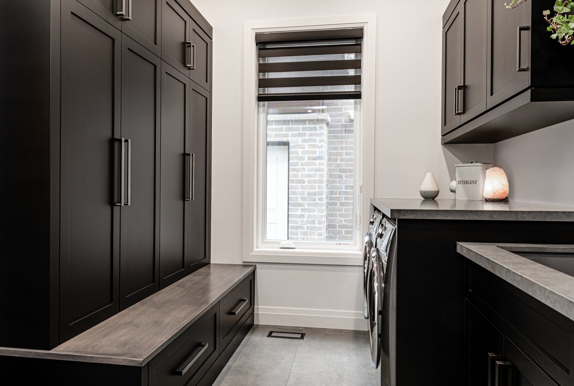 A laundry room with black cabinets , a washer and dryer , and a window.
