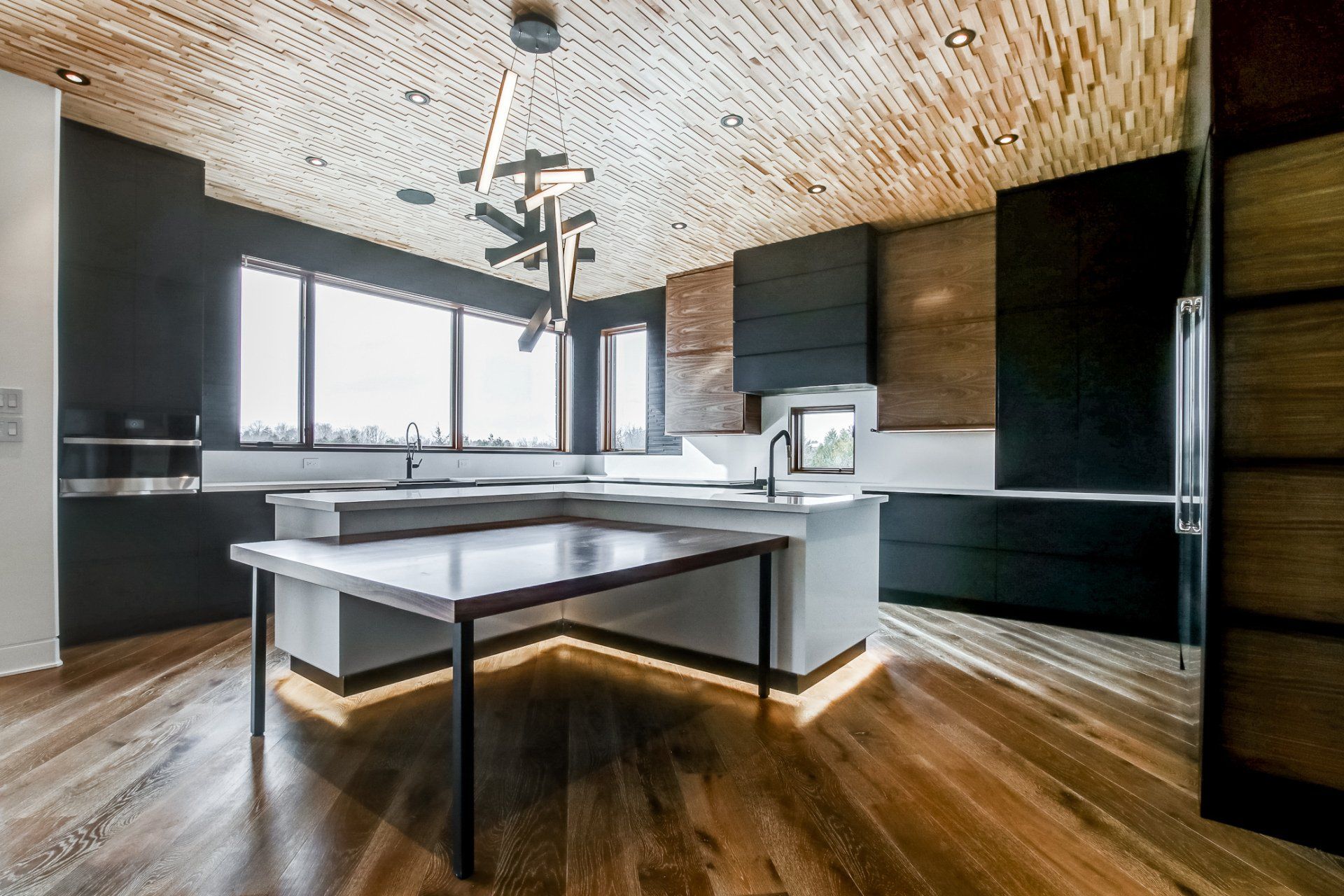 A kitchen with a large island in the middle and a wooden floor.