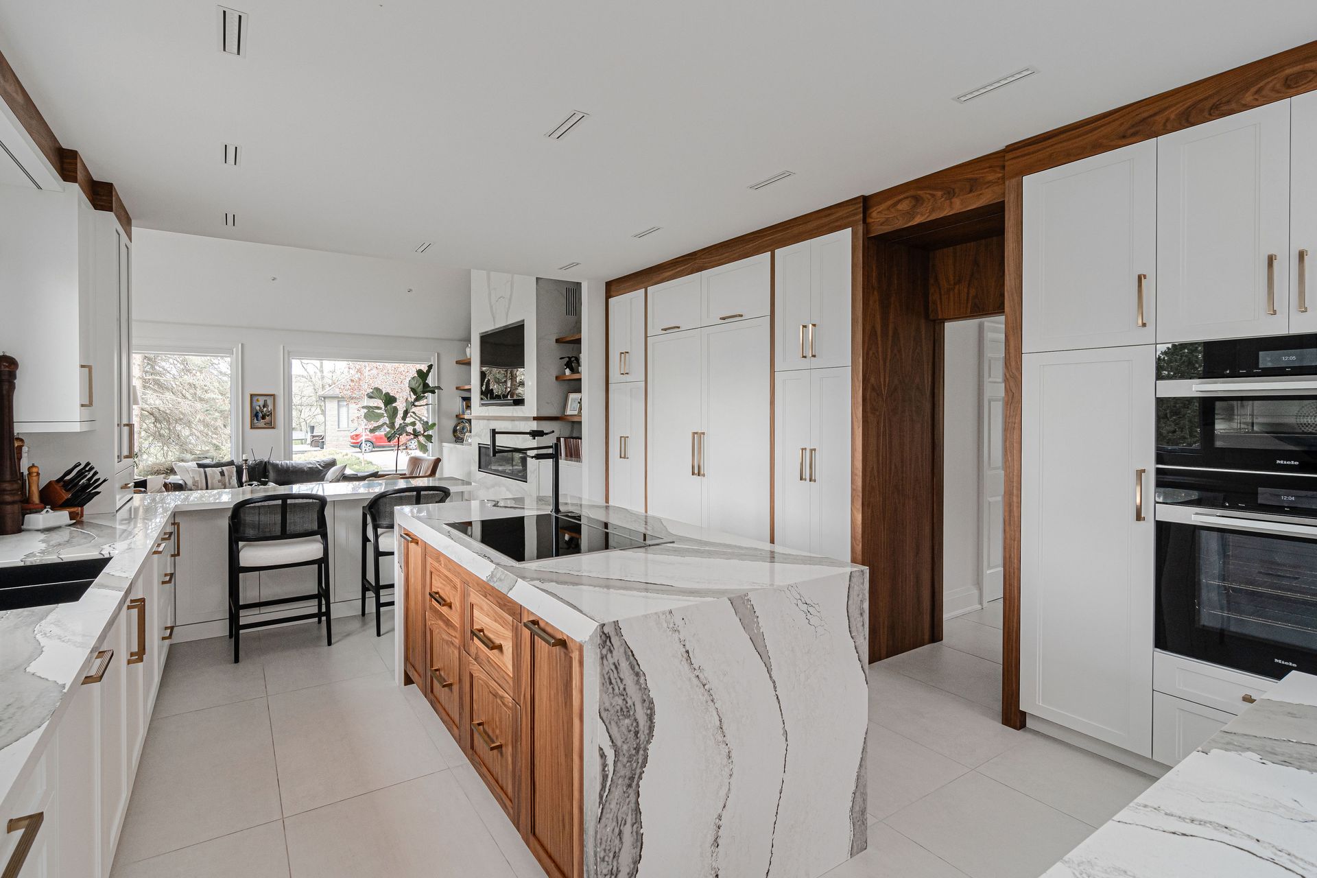 A kitchen with white cabinets and wooden cabinets and a large island in the middle.