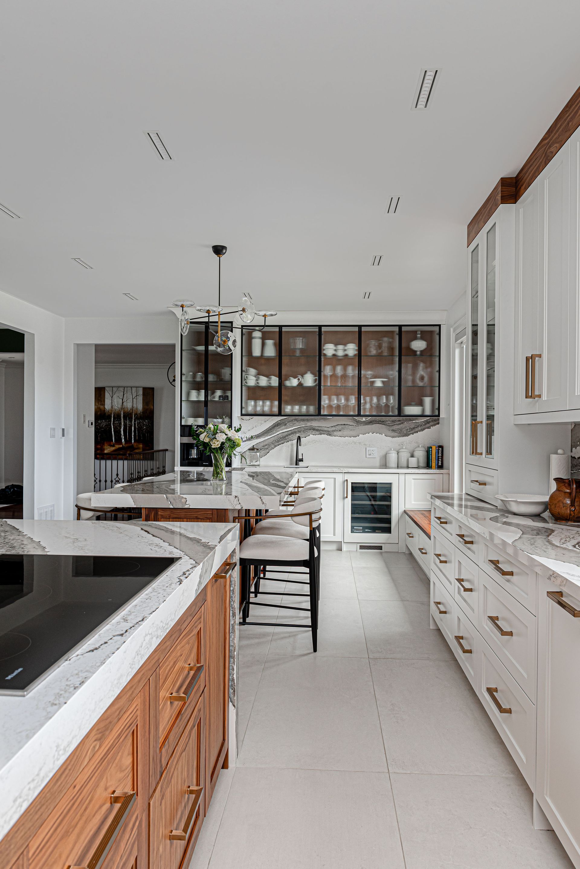 A kitchen with white cabinets , wooden cabinets , marble counter tops , and a large island.