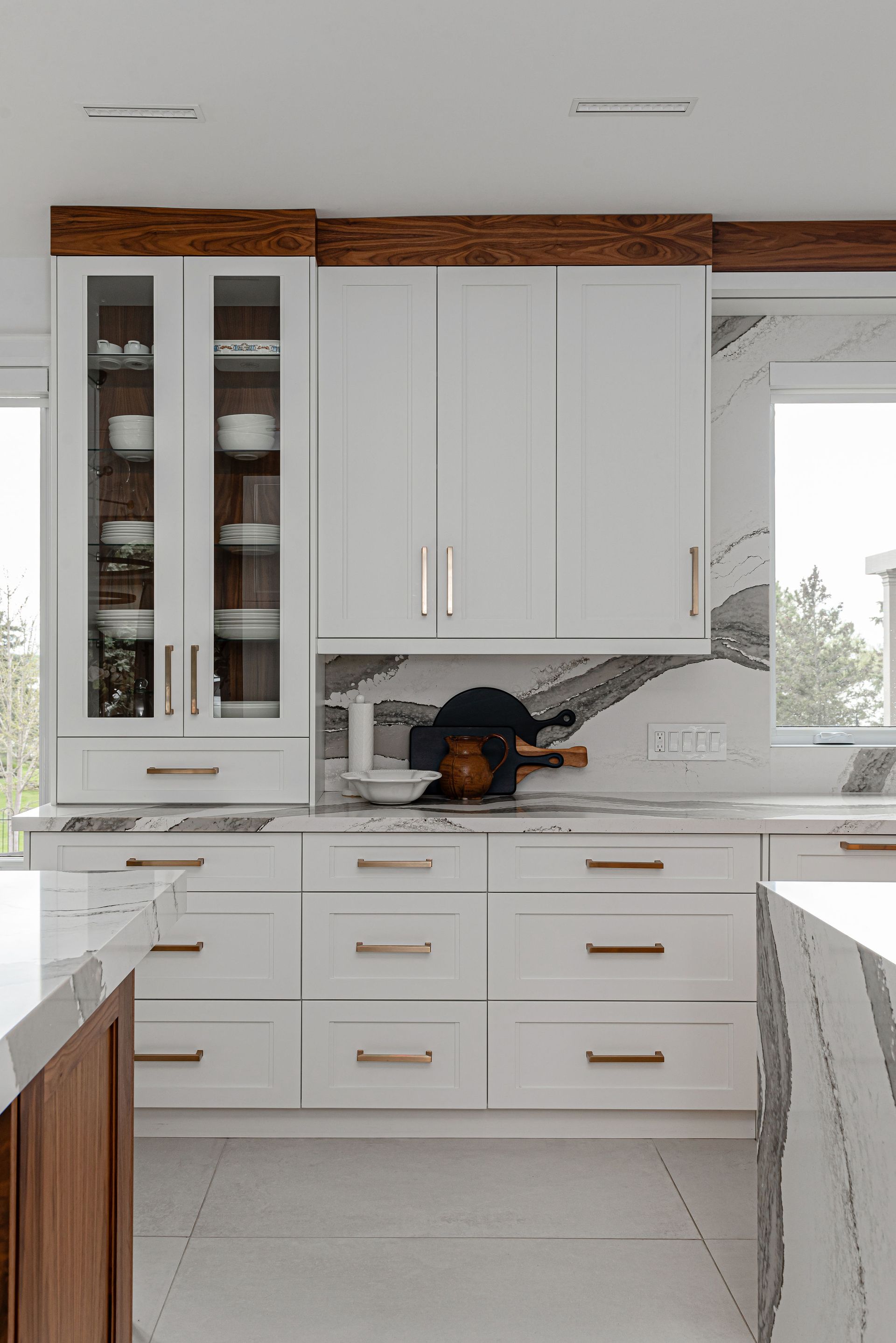 A kitchen with white cabinets and marble counter tops.