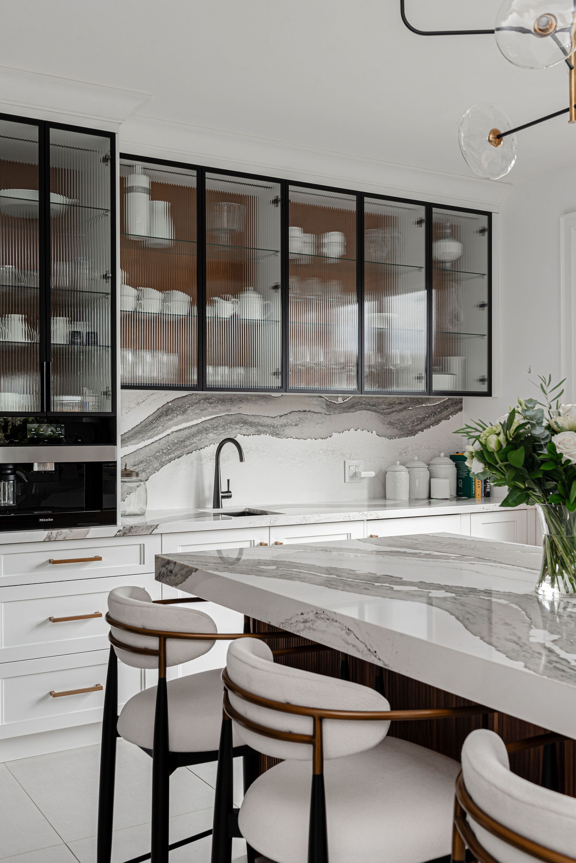A kitchen with a table and chairs and a vase of flowers on the counter.