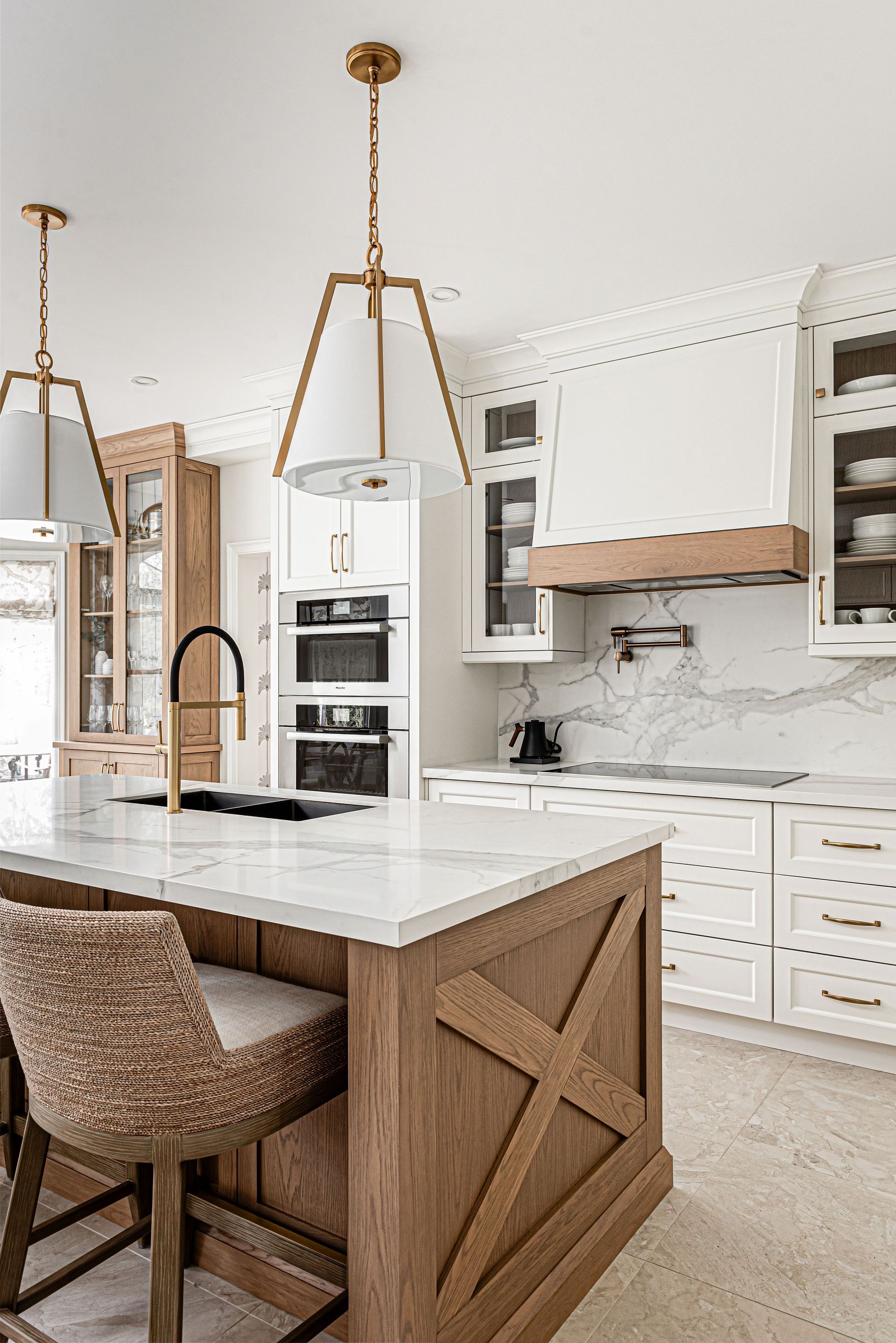 A kitchen with white cabinets , a large island , a sink , and a faucet.