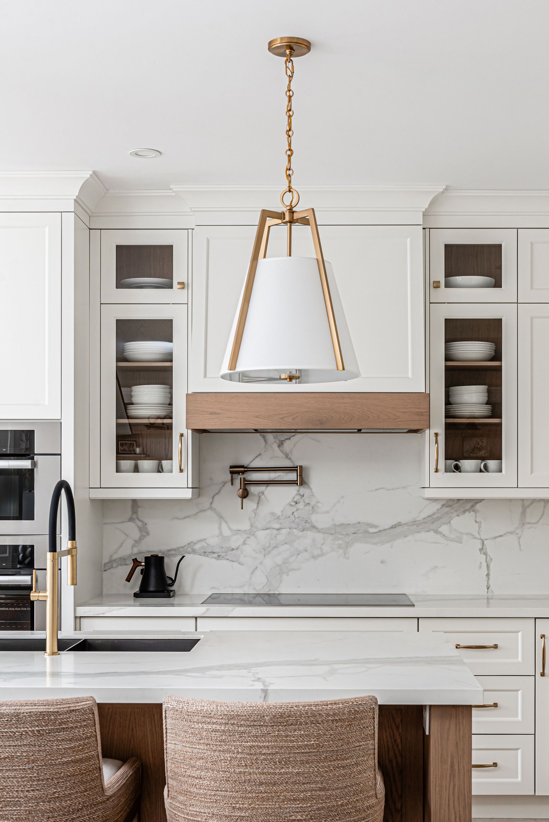 A kitchen with white cabinets , marble counter tops , a sink , and a stove.