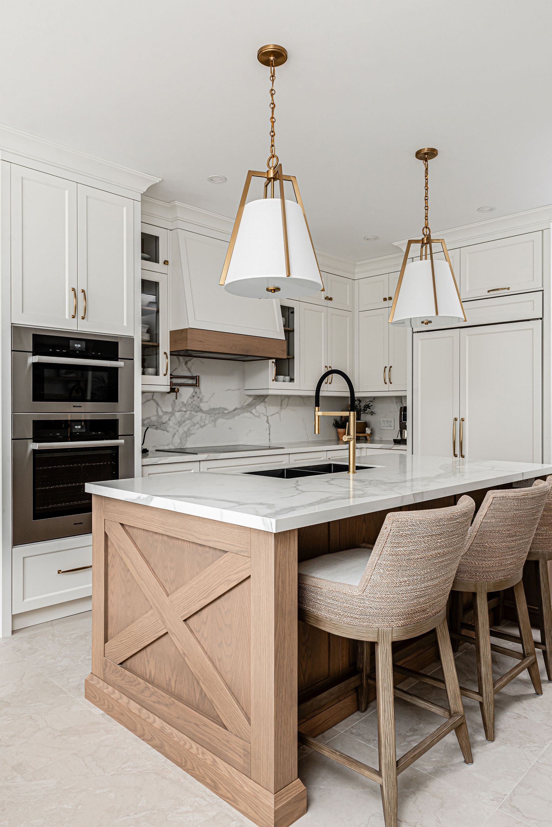 A kitchen with white cabinets , a wooden island , stools , and a sink.