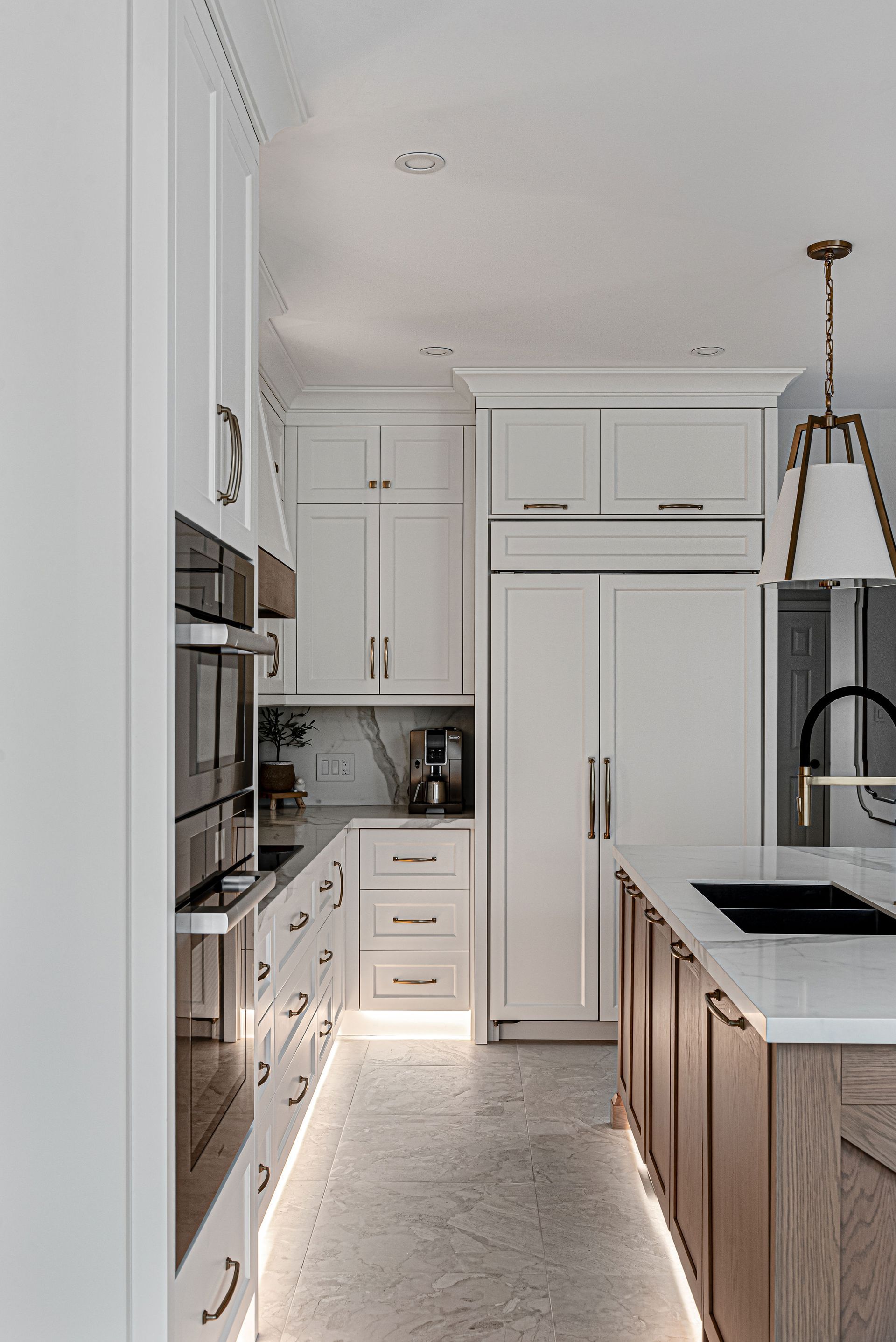 A kitchen with white cabinets , wooden cabinets , a sink , and a refrigerator.