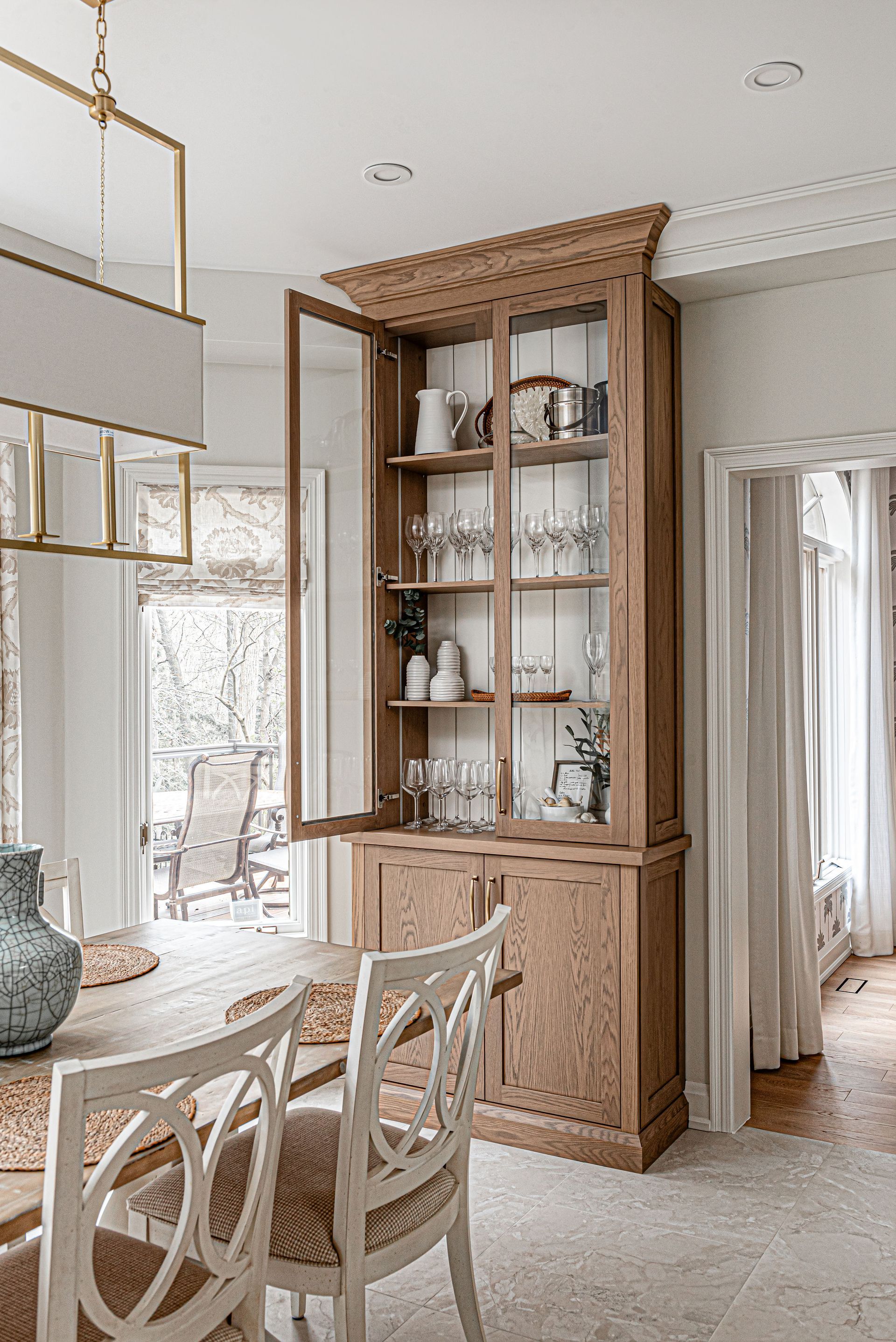A dining room with a table and chairs and a hutch with the doors open.
