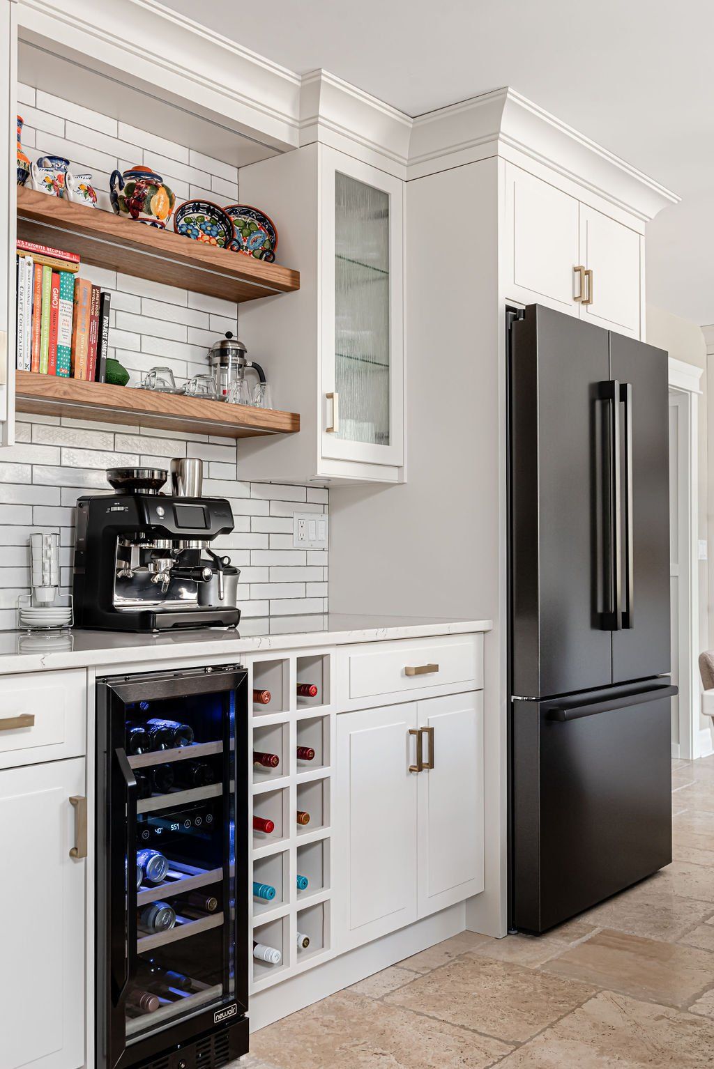 A kitchen with white cabinets , a black refrigerator , a wine cooler and a coffee maker.
