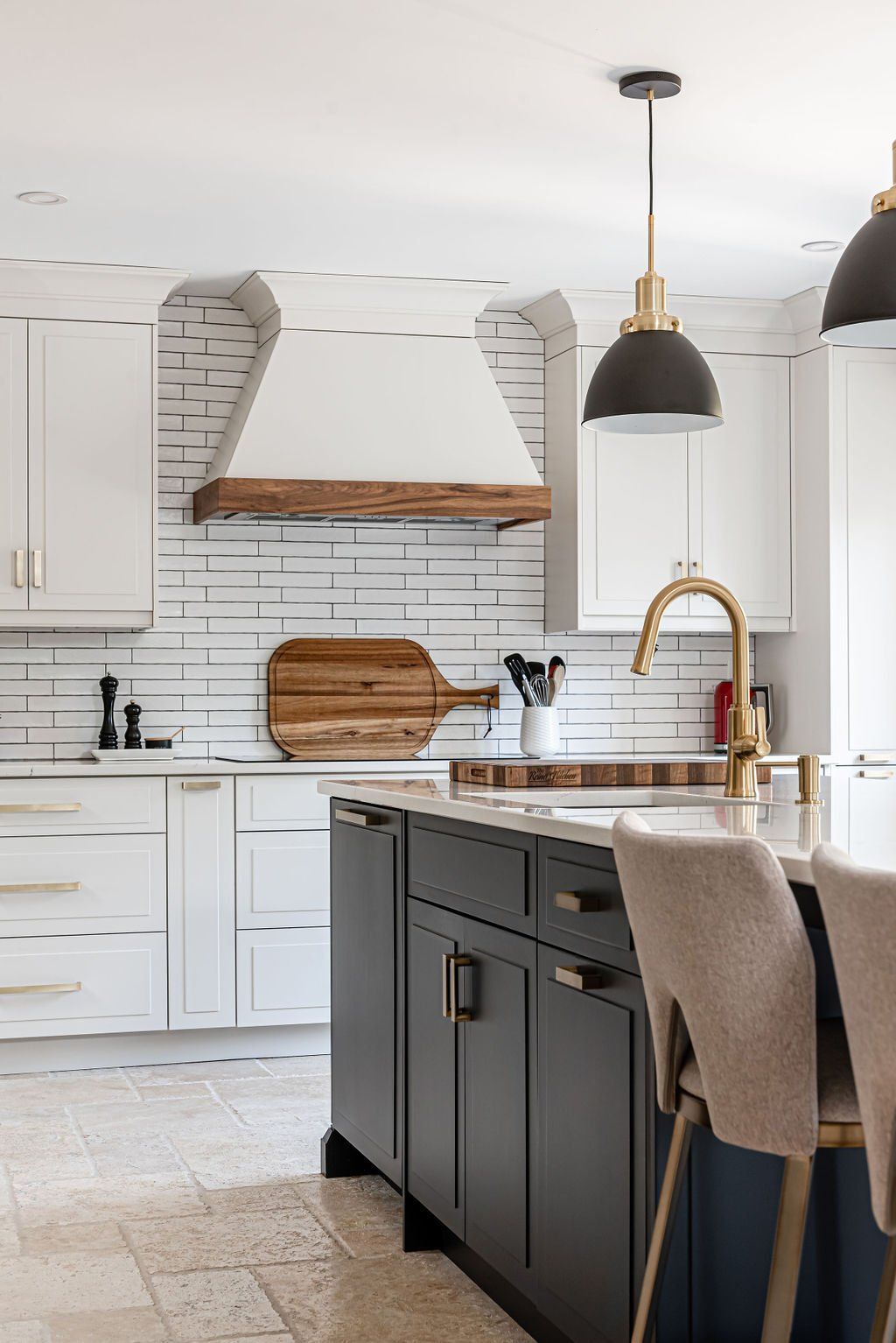 A kitchen with white cabinets , a large island , a sink , and a wooden cutting board.