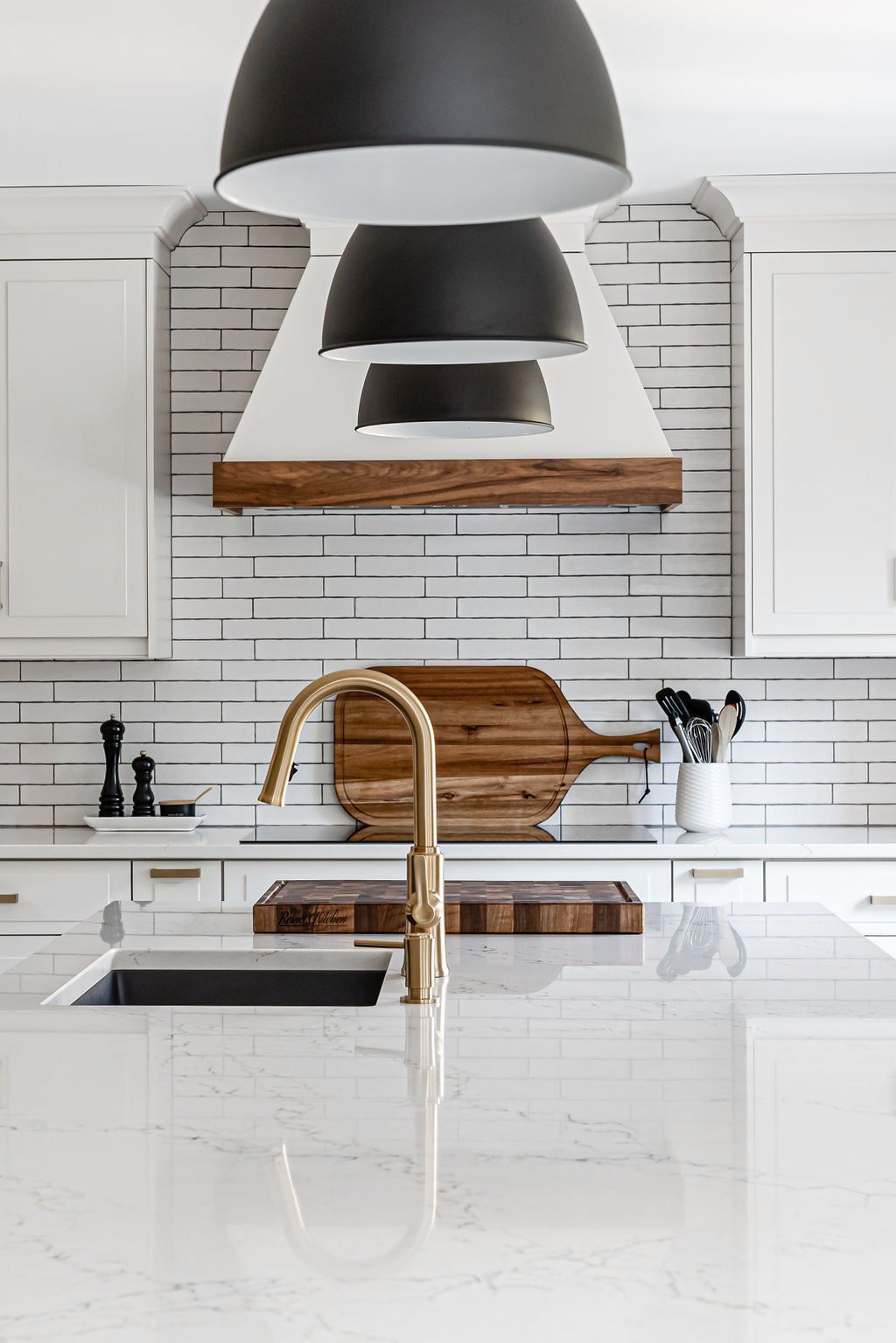 A kitchen with white cabinets , a sink , and a wooden cutting board on the counter.