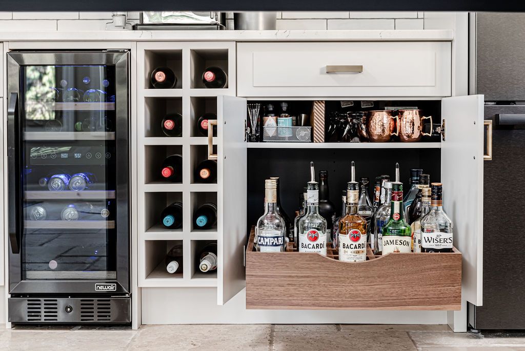 A kitchen with a wine cooler and a bar with bottles of liquor.