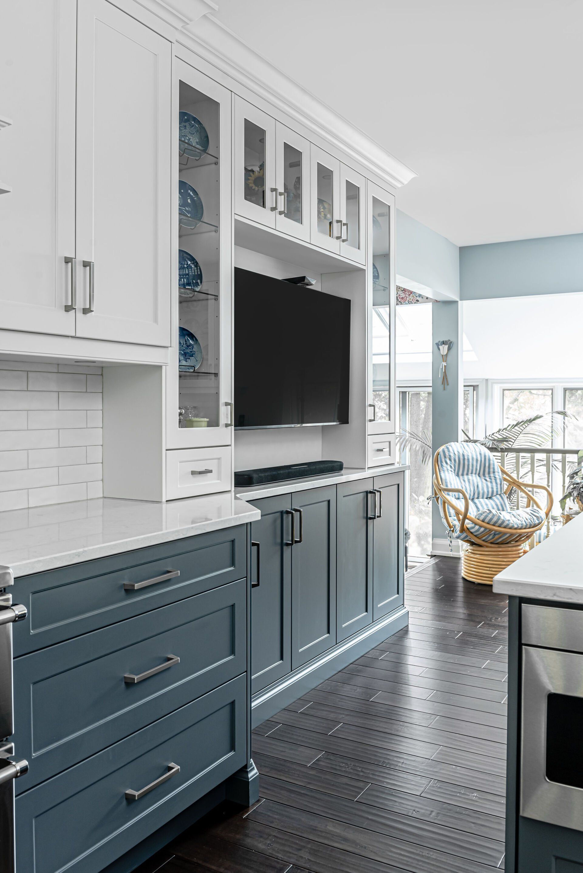 A kitchen with blue cabinets and a flat screen tv on the wall.