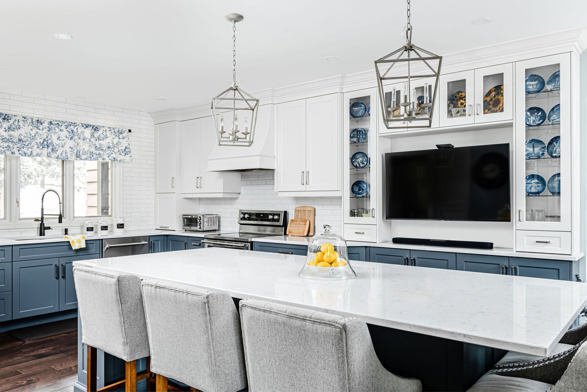 A kitchen with a large island , chairs , a table and a flat screen tv.
