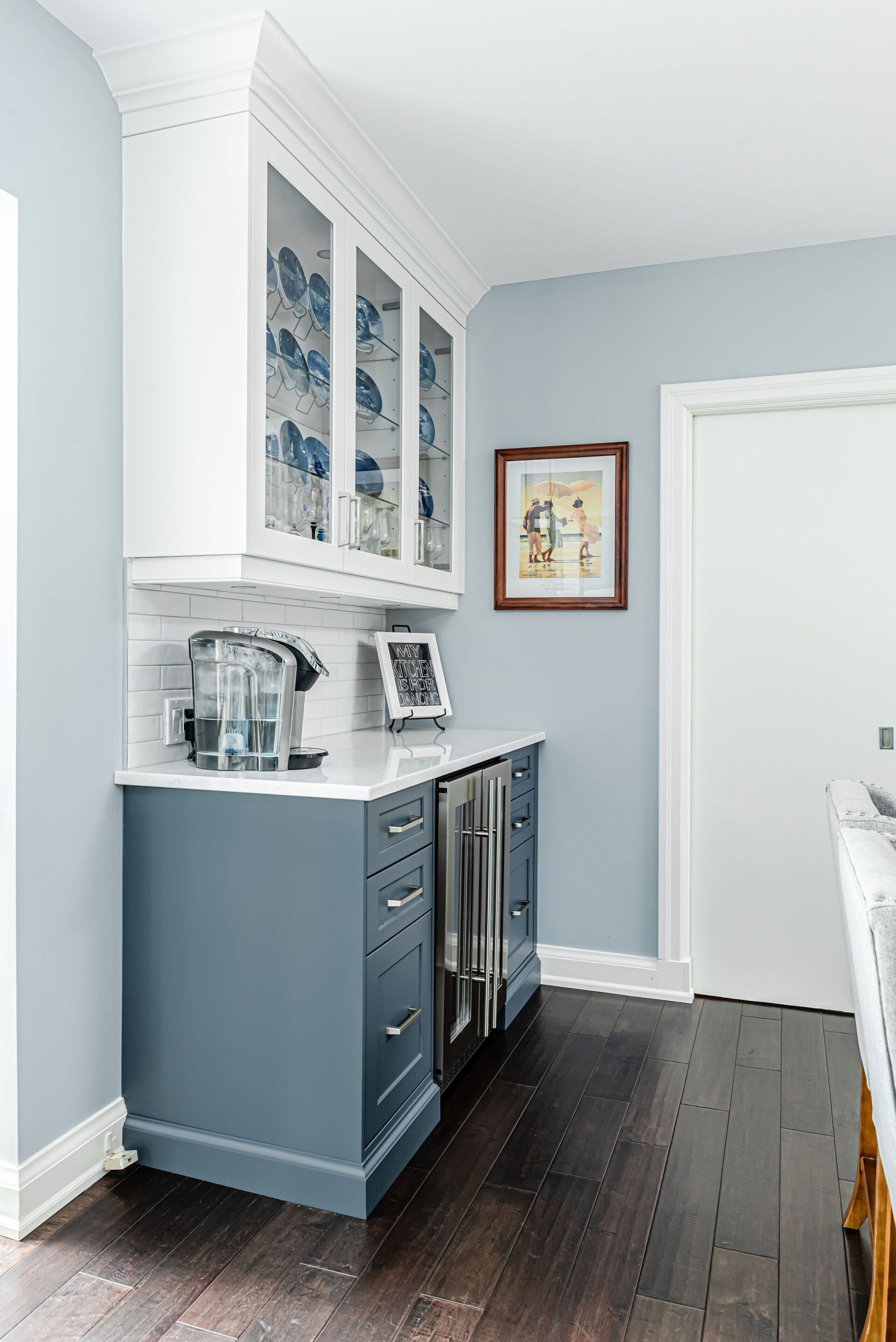 A kitchen with blue cabinets , white cabinets and a refrigerator.