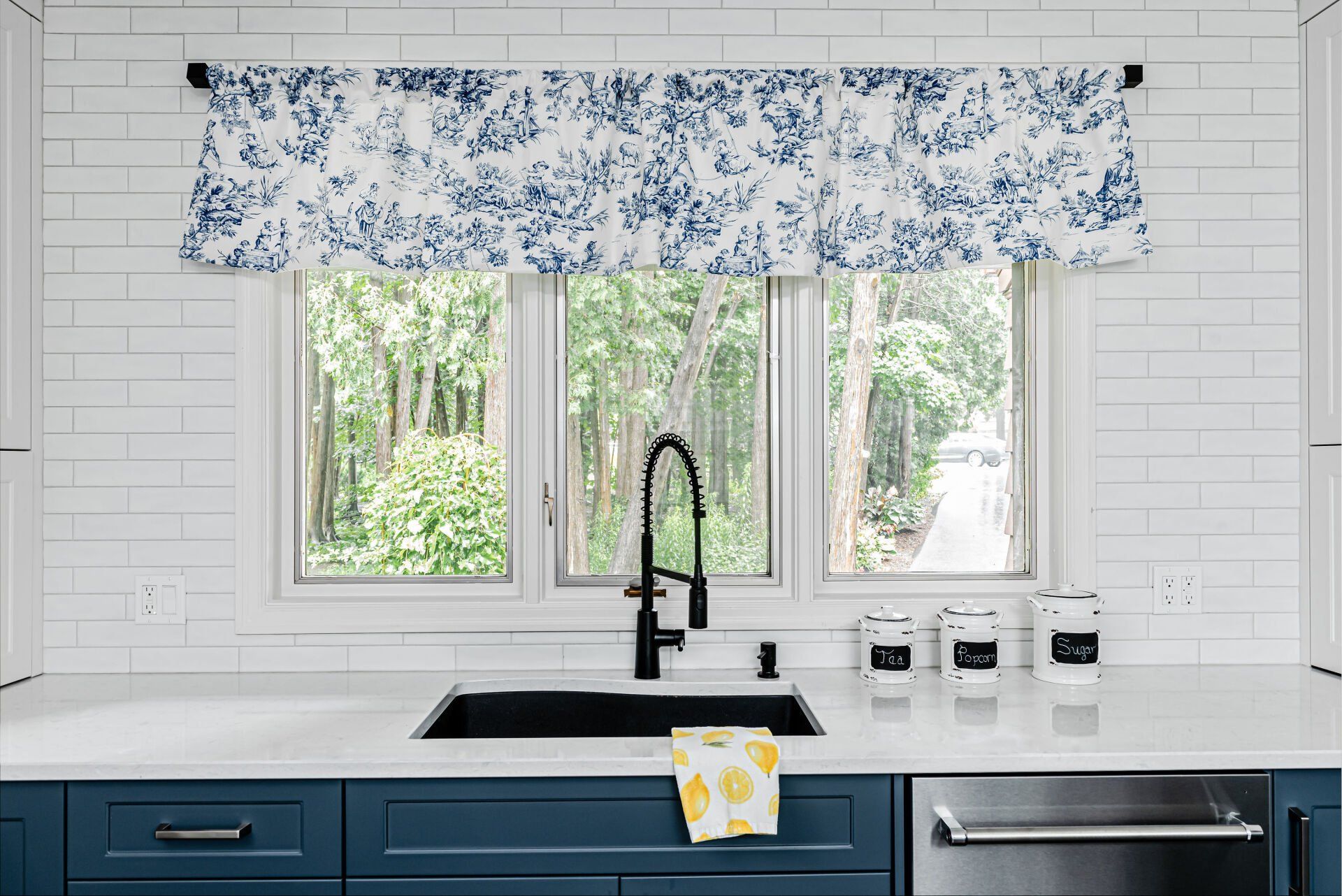A kitchen with a sink , dishwasher , and window.