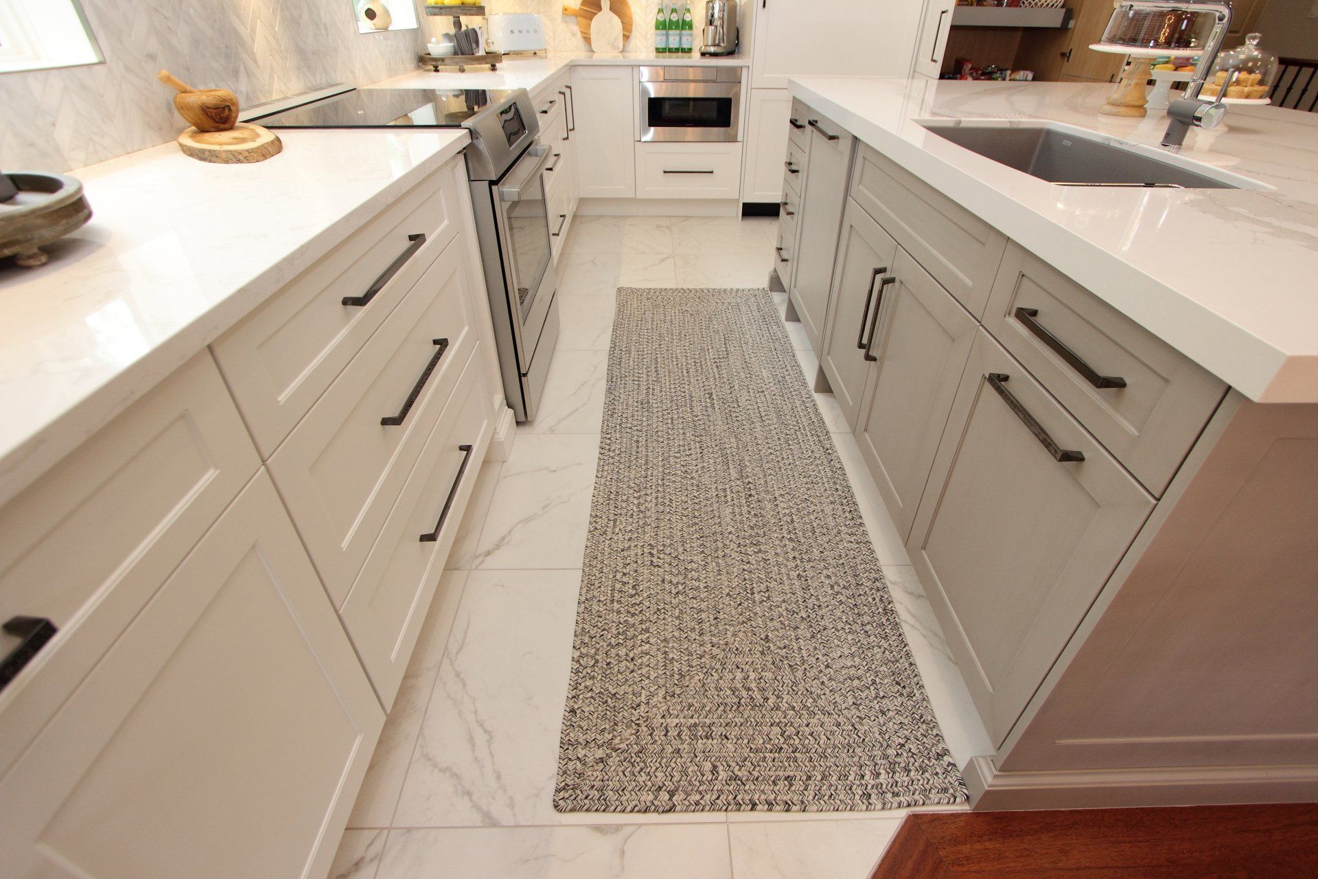 A kitchen with white cabinets and a rug on the floor