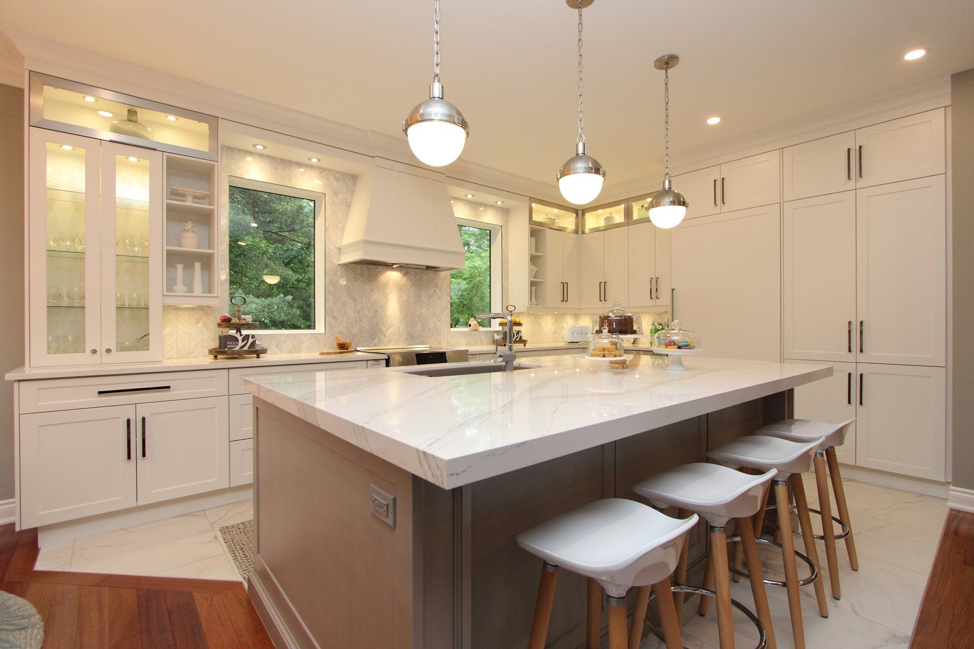 A kitchen with white cabinets and stools and a large island.