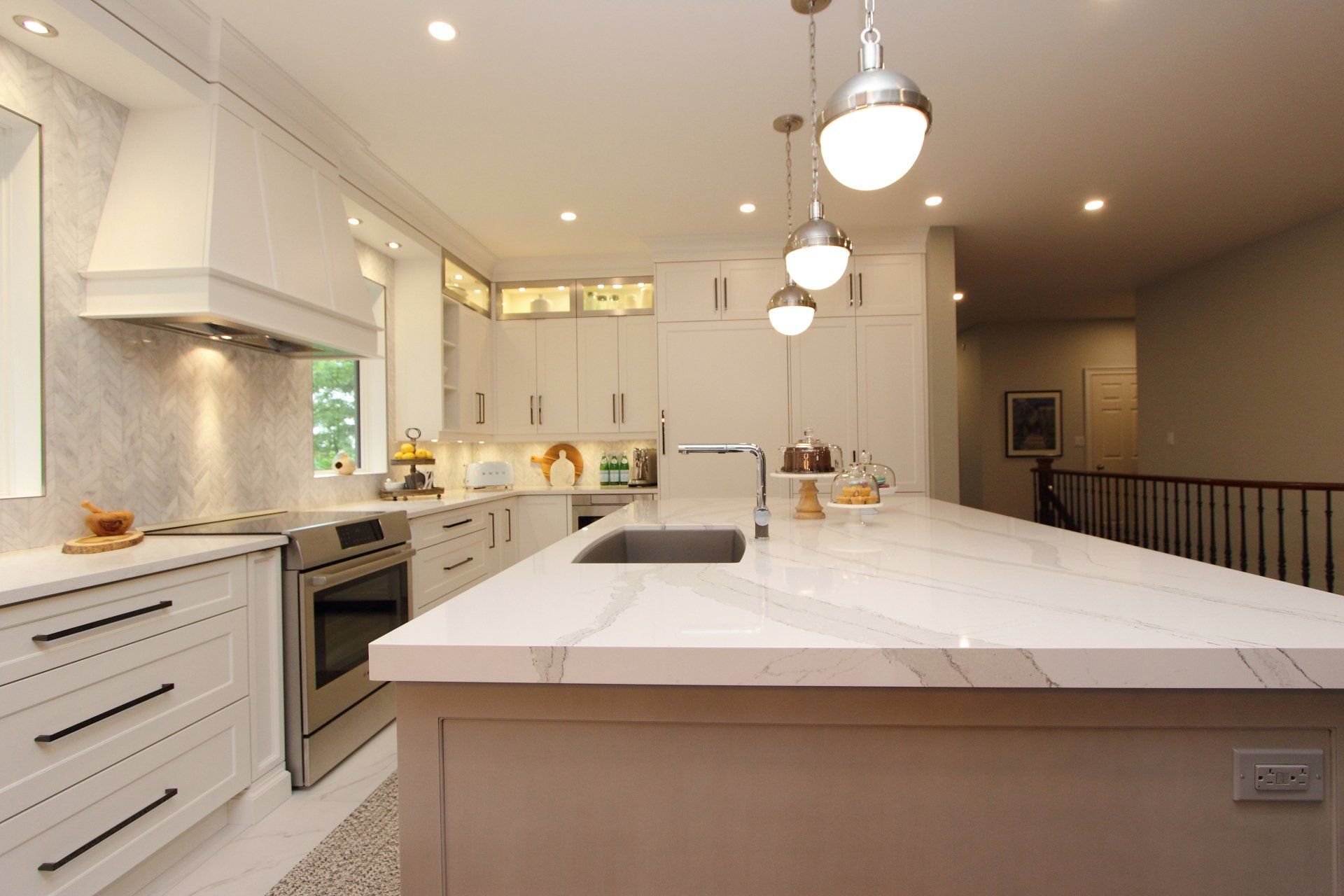 A kitchen with white cabinets and a large island with a sink.