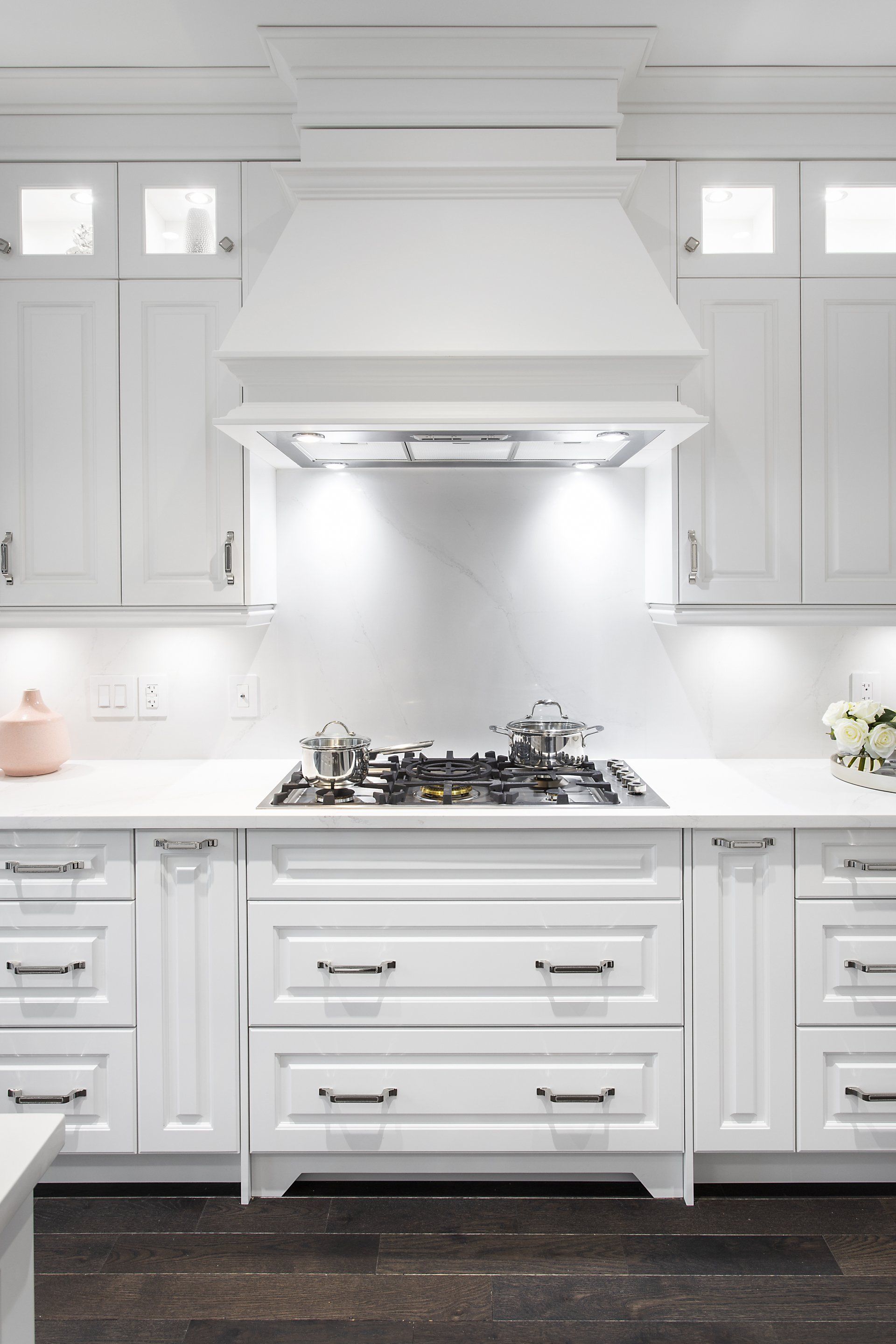 A kitchen with white cabinets and a stove top oven.