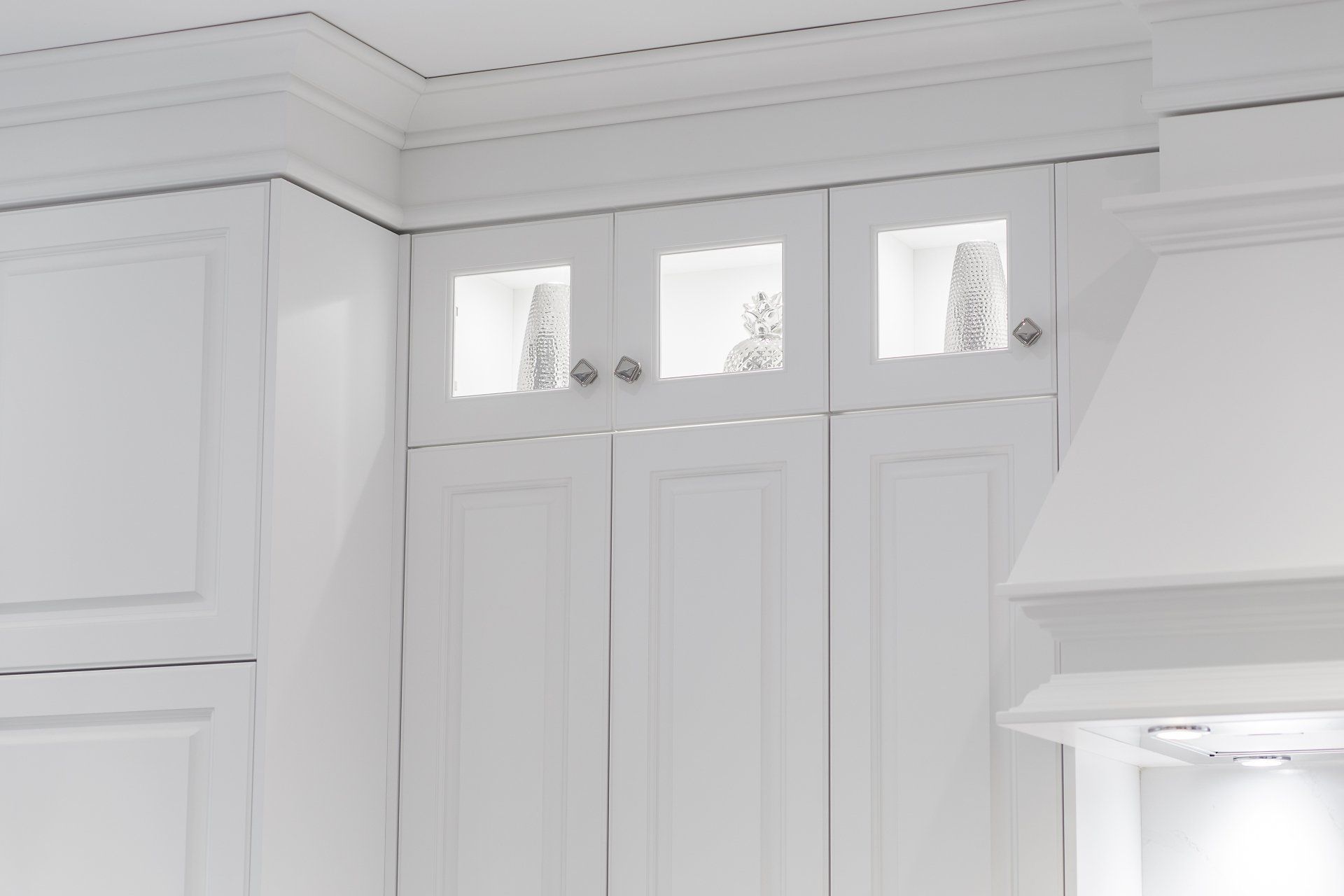 A kitchen with white cabinets and a hood.