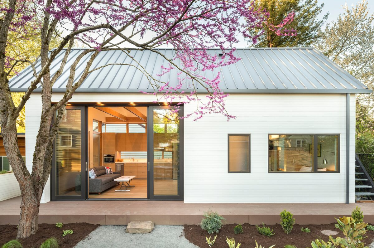 A small white house with a metal roof and sliding glass doors