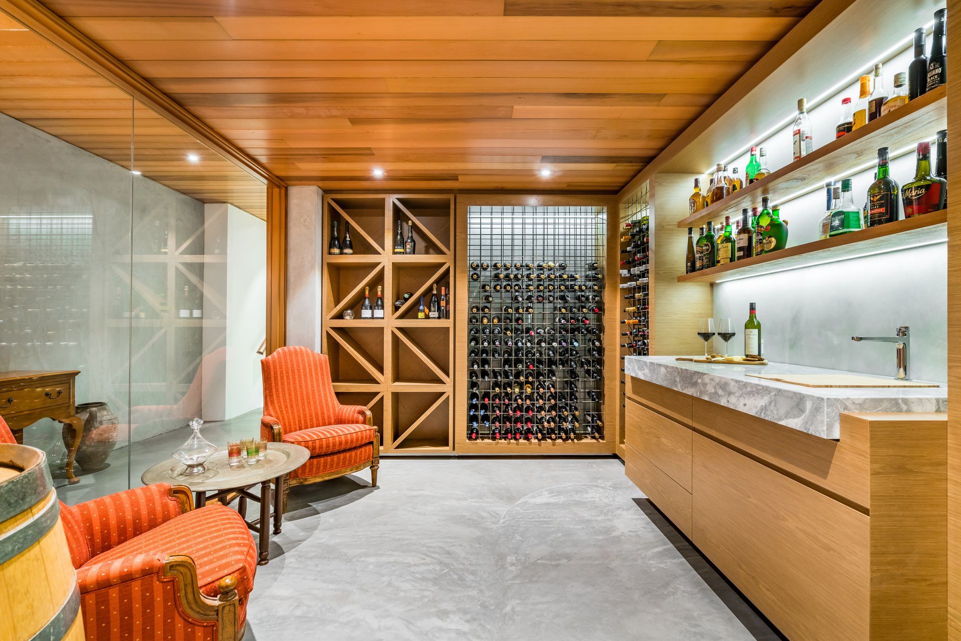 A wine cellar with a bar , chairs , shelves and bottles of wine.