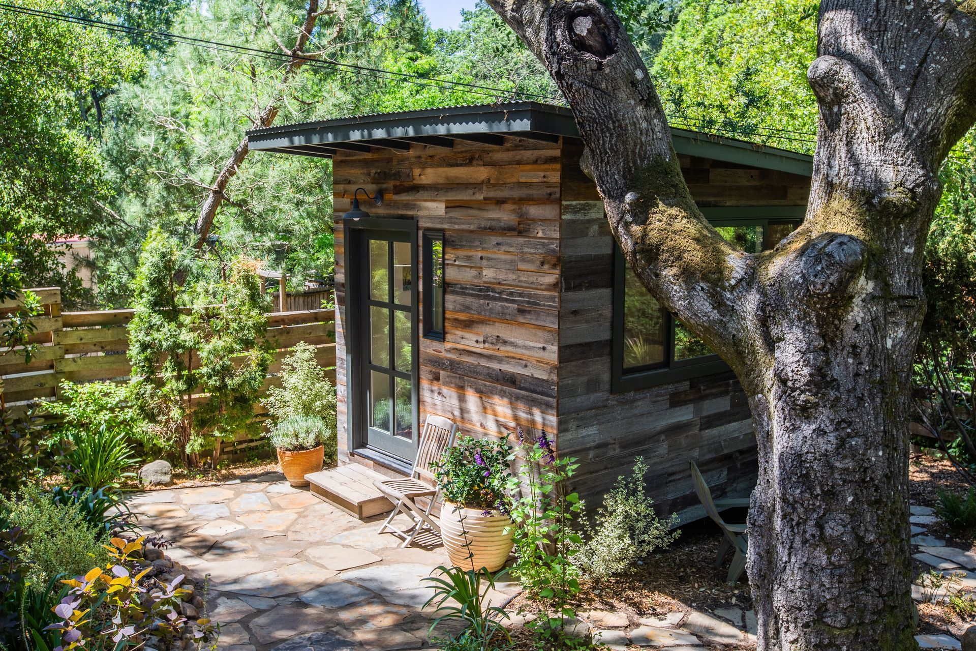 A small wooden house in the middle of a forest surrounded by trees.