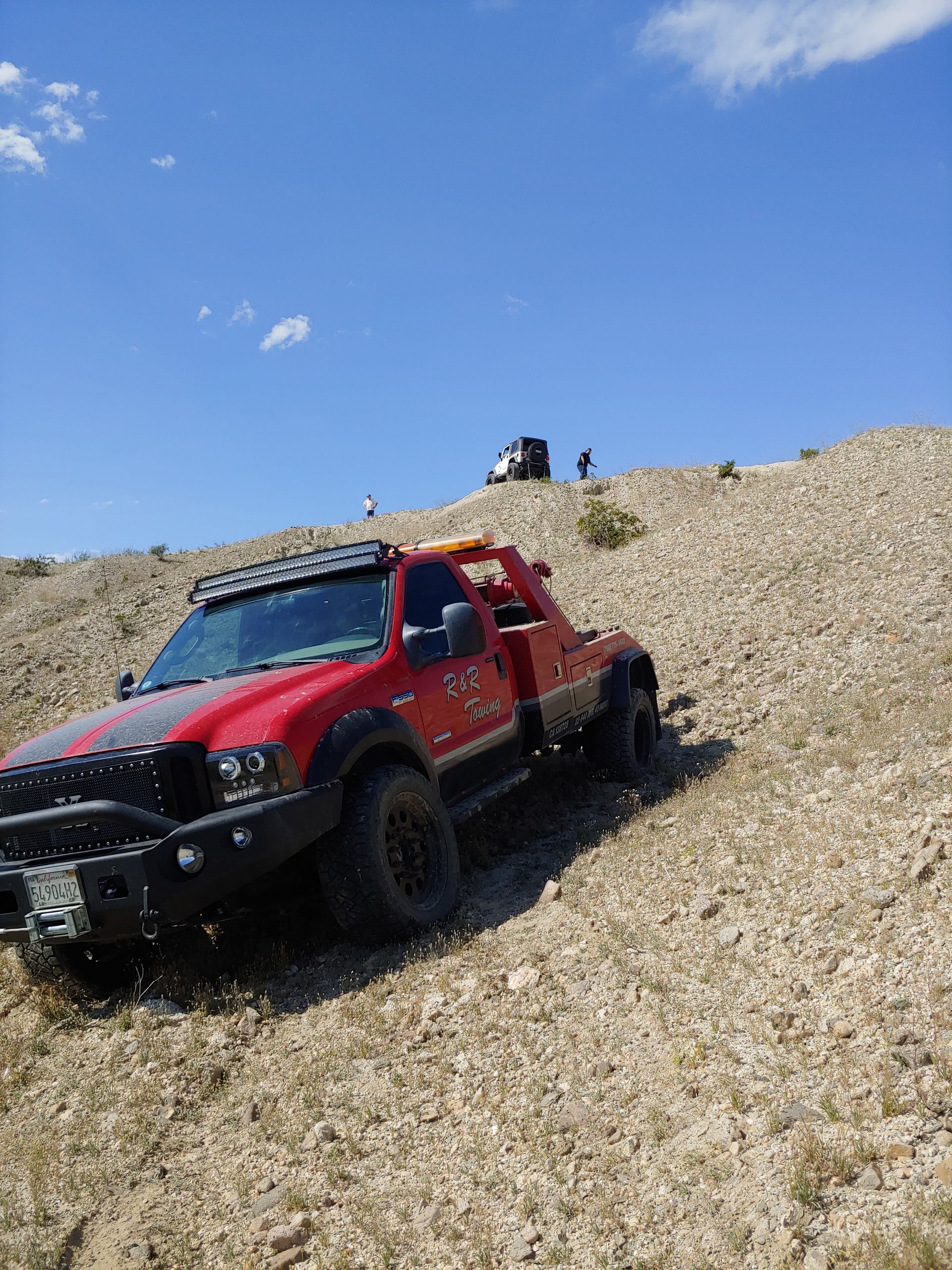 A red truck is driving down a dirt hill.