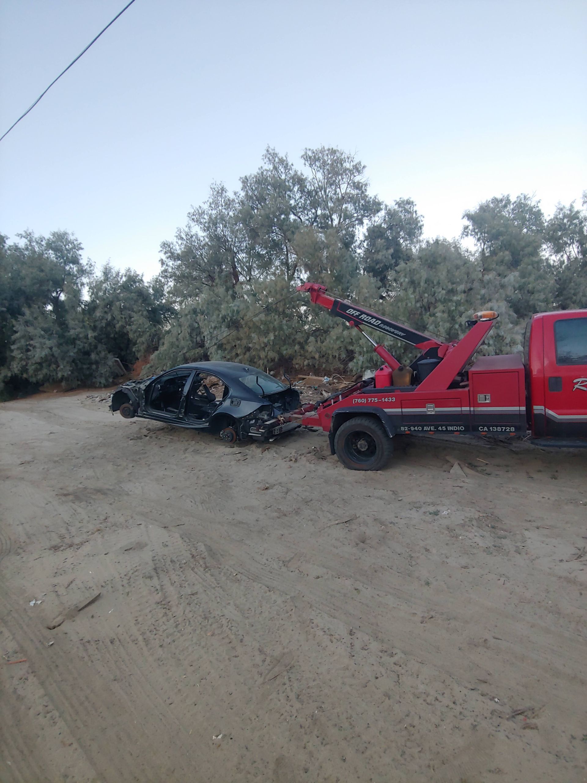 A wrecked car is being towed by a tow truck