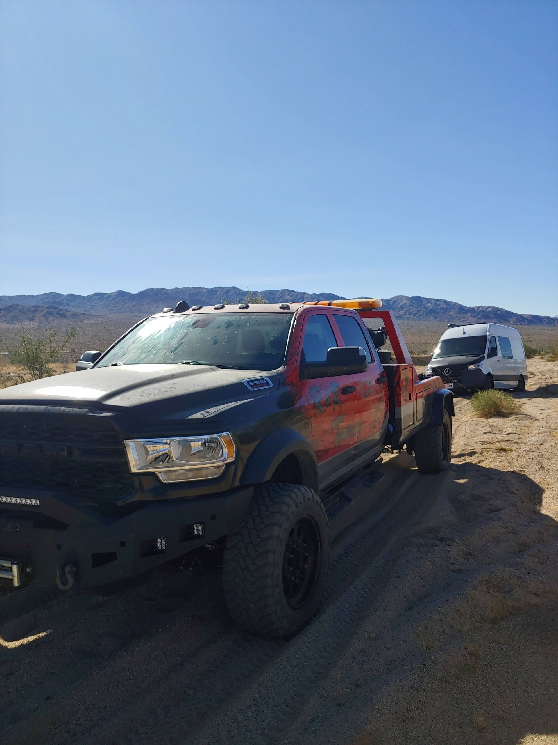 A tow truck is parked on the side of a dirt road.