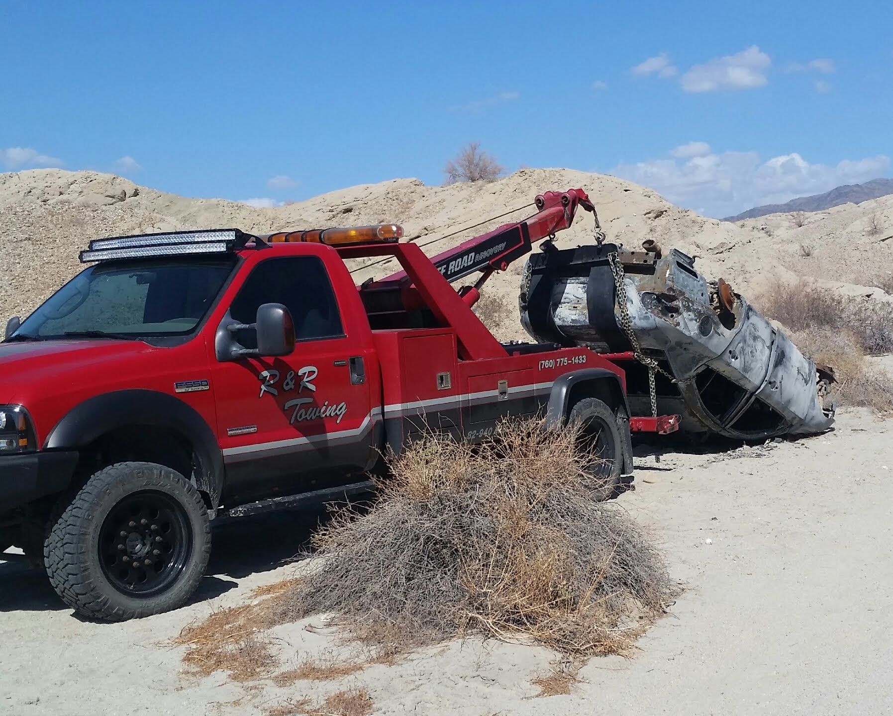 A red tow truck is carrying a wrecked car