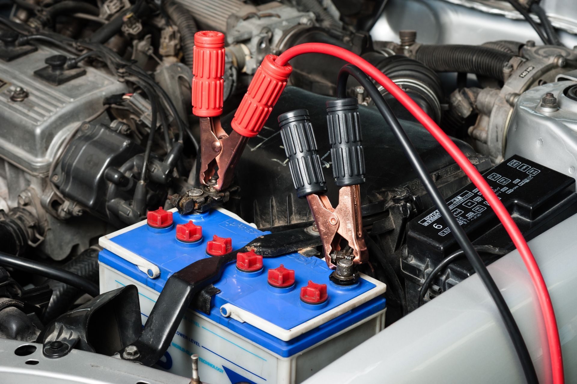 A car battery is being charged with jumper cables.
