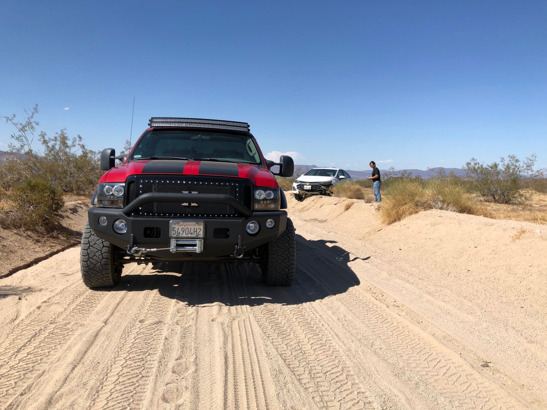 A red truck is driving down a dirt road.