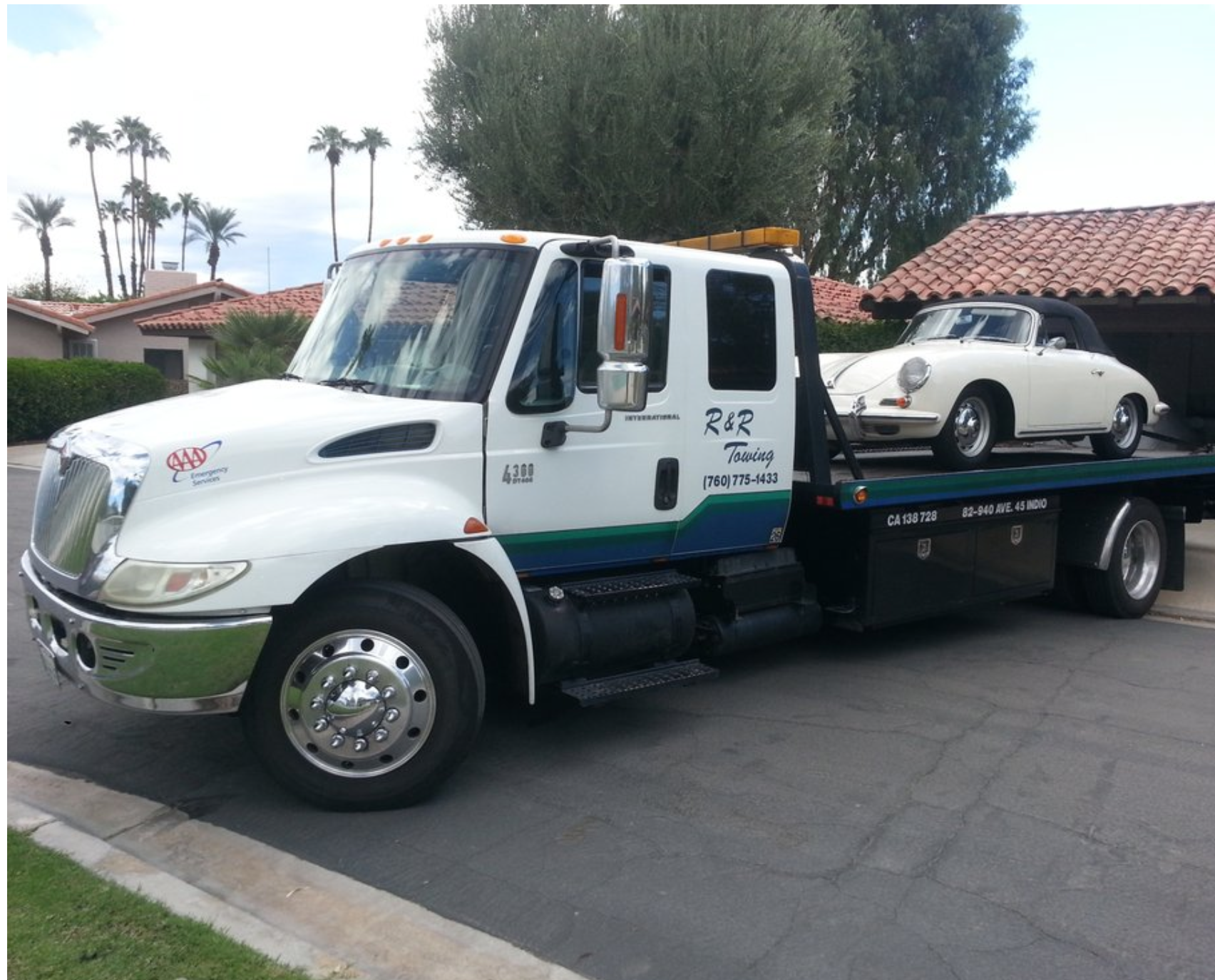 A tow truck with a porsche on the back of it