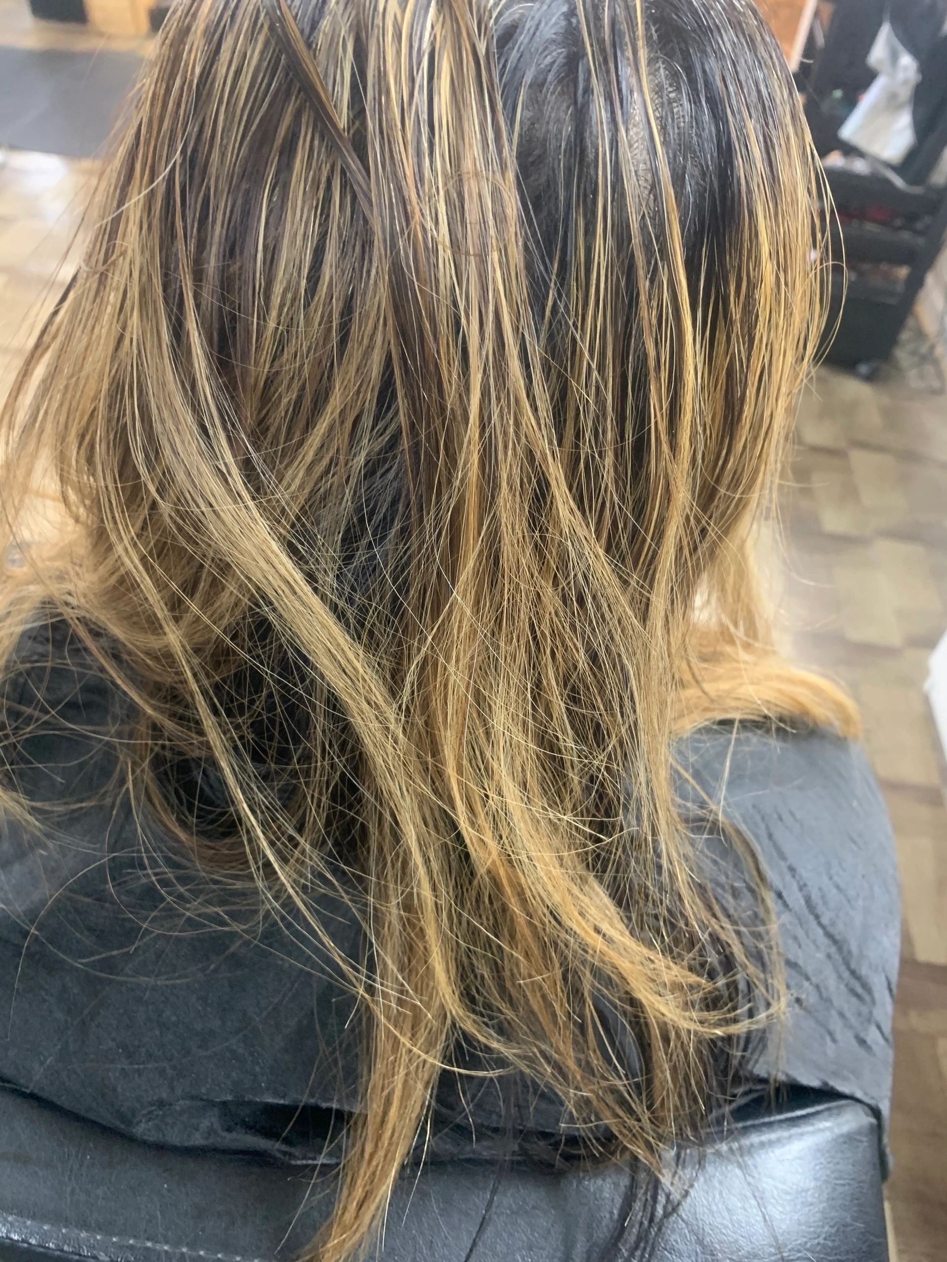 A woman with long hair is sitting in a chair in a salon.