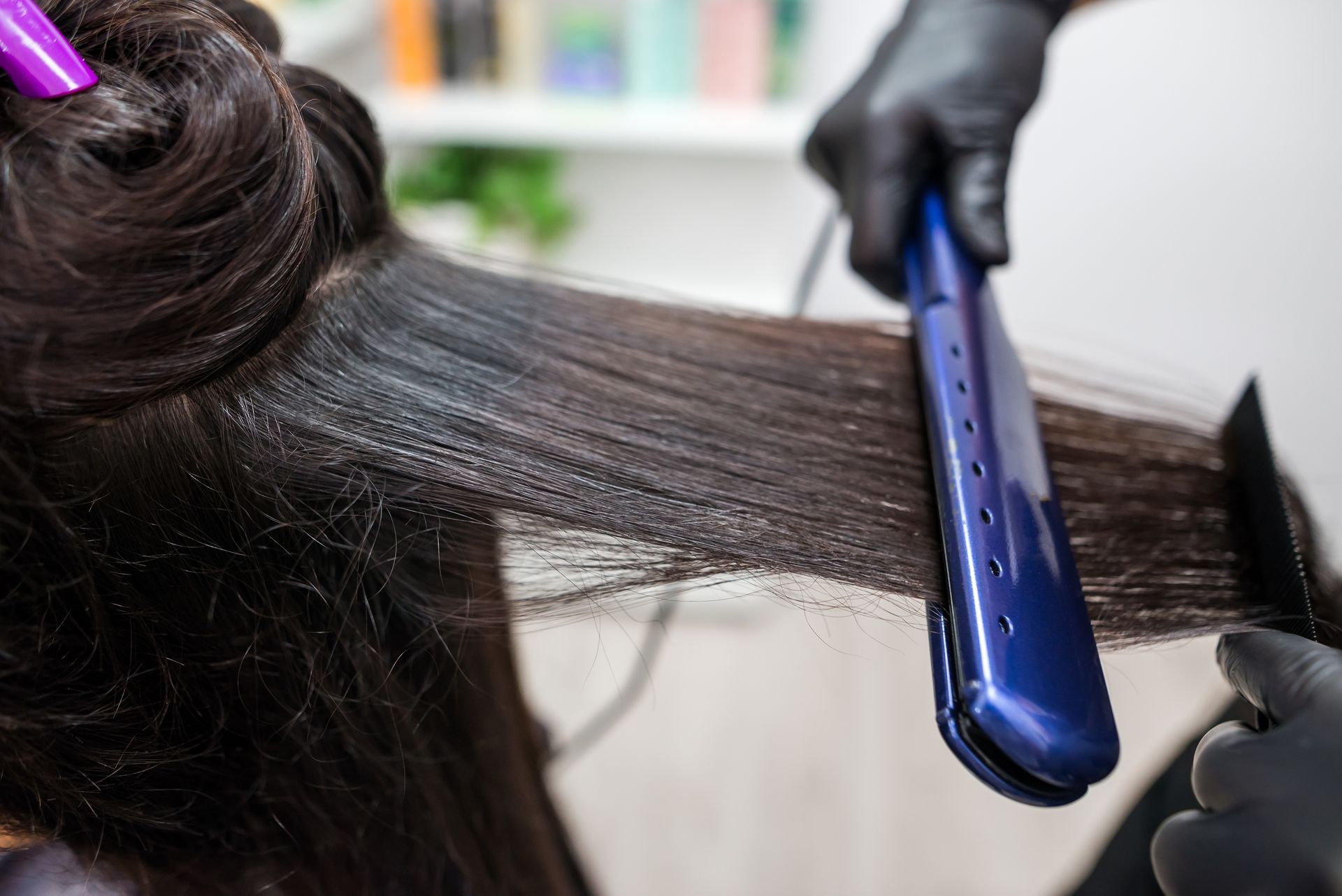 A woman is getting her hair straightened by a hairdresser.