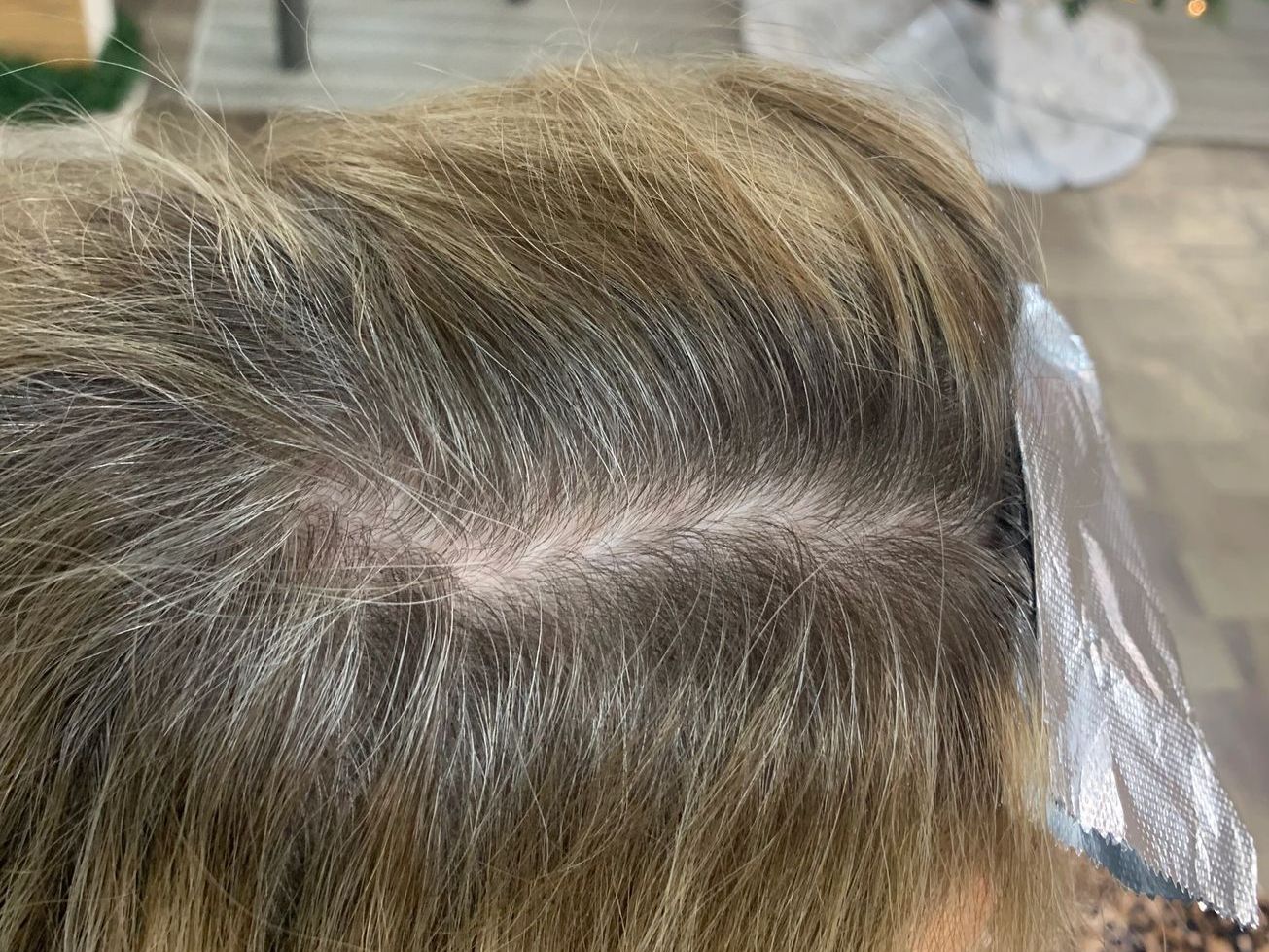 A close up of a woman 's hair with a piece of foil on it.