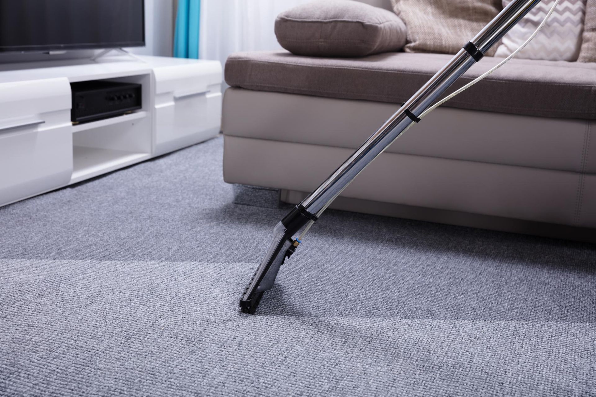 A vacuum cleaner is cleaning a carpet in a living room.
