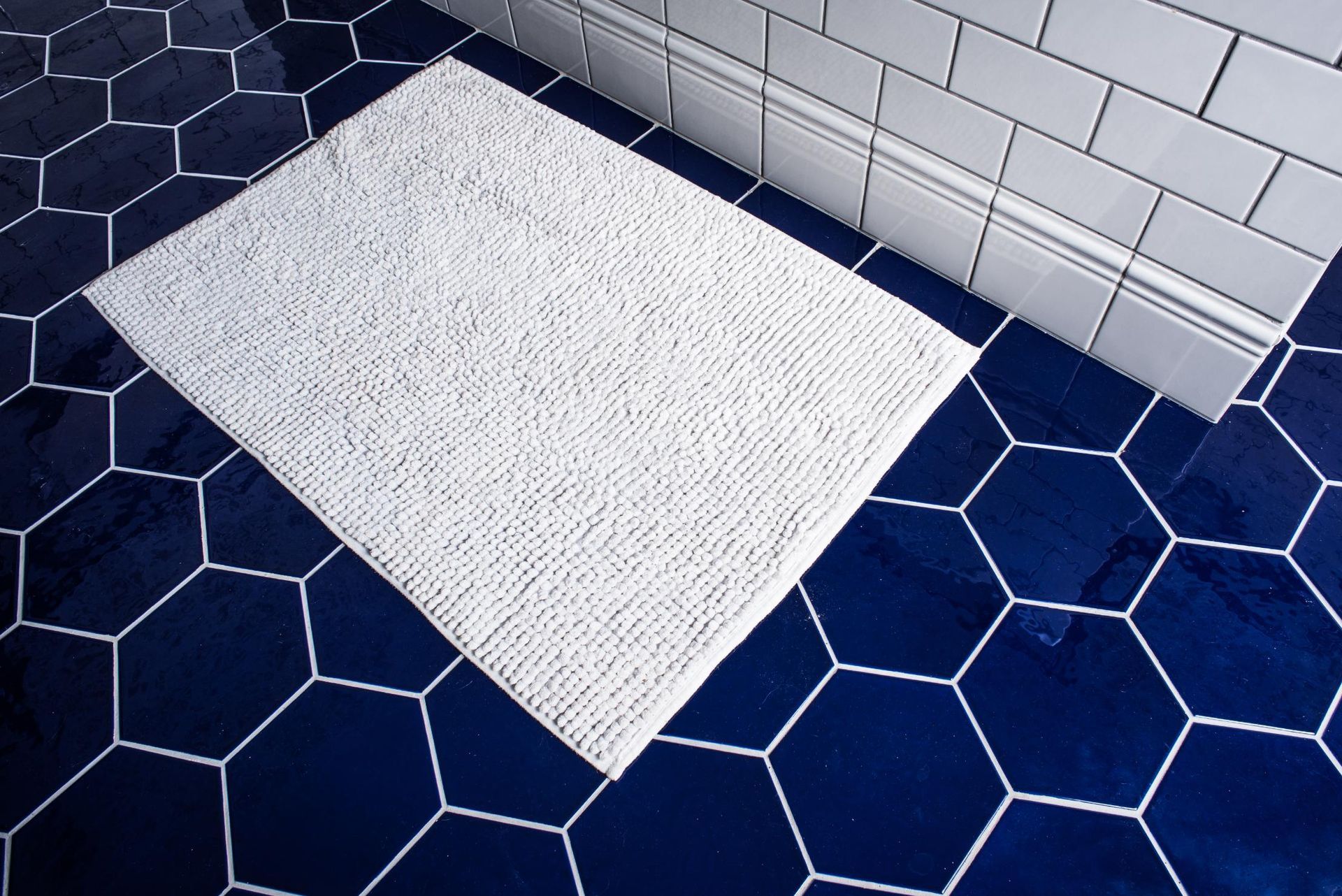 A white rug is sitting on a blue tiled floor.