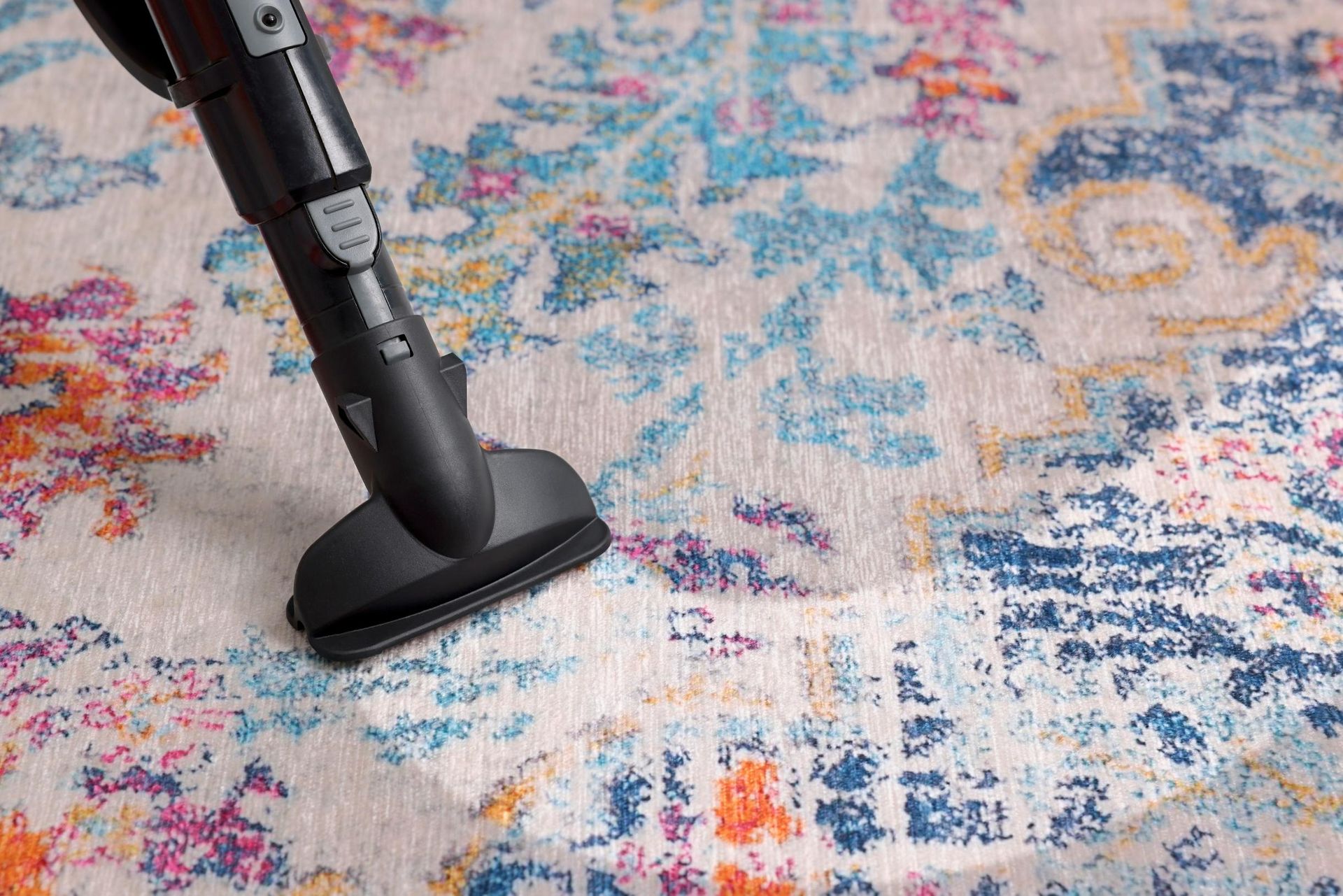 A person is using a vacuum cleaner to clean a rug.