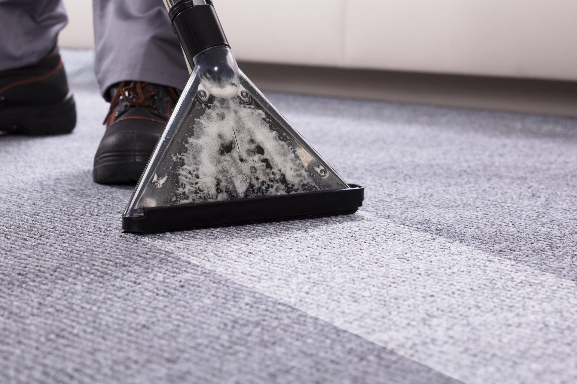 A person is cleaning a carpet with a vacuum cleaner.