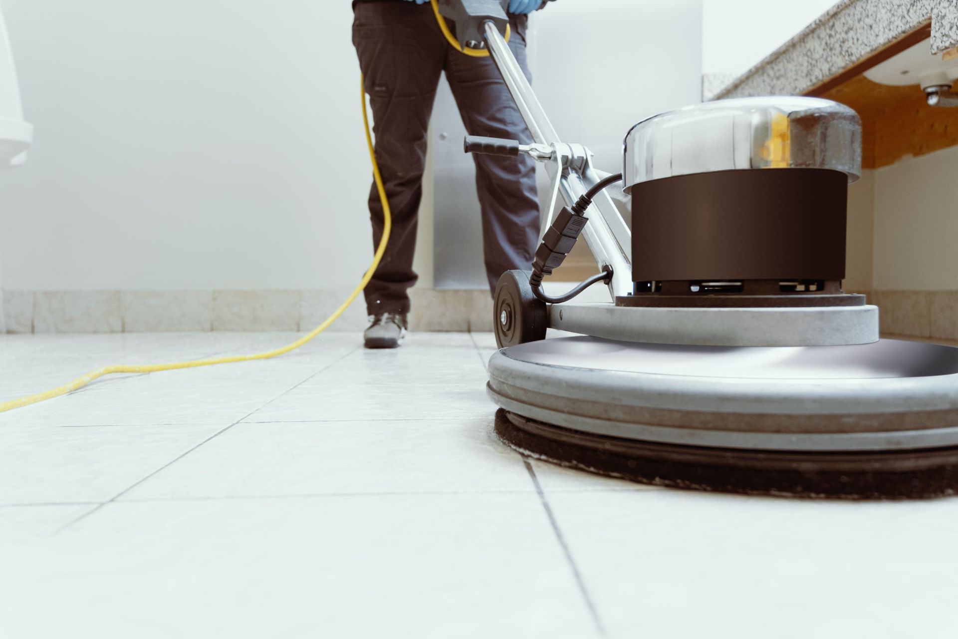 A man is using a machine to clean a tile floor.