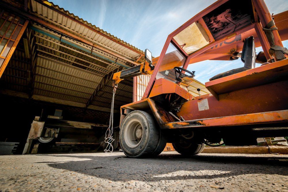 An Orange Forklift is Parked in Front of a Building — Trucking Crane Trucks in Gympie, QLD